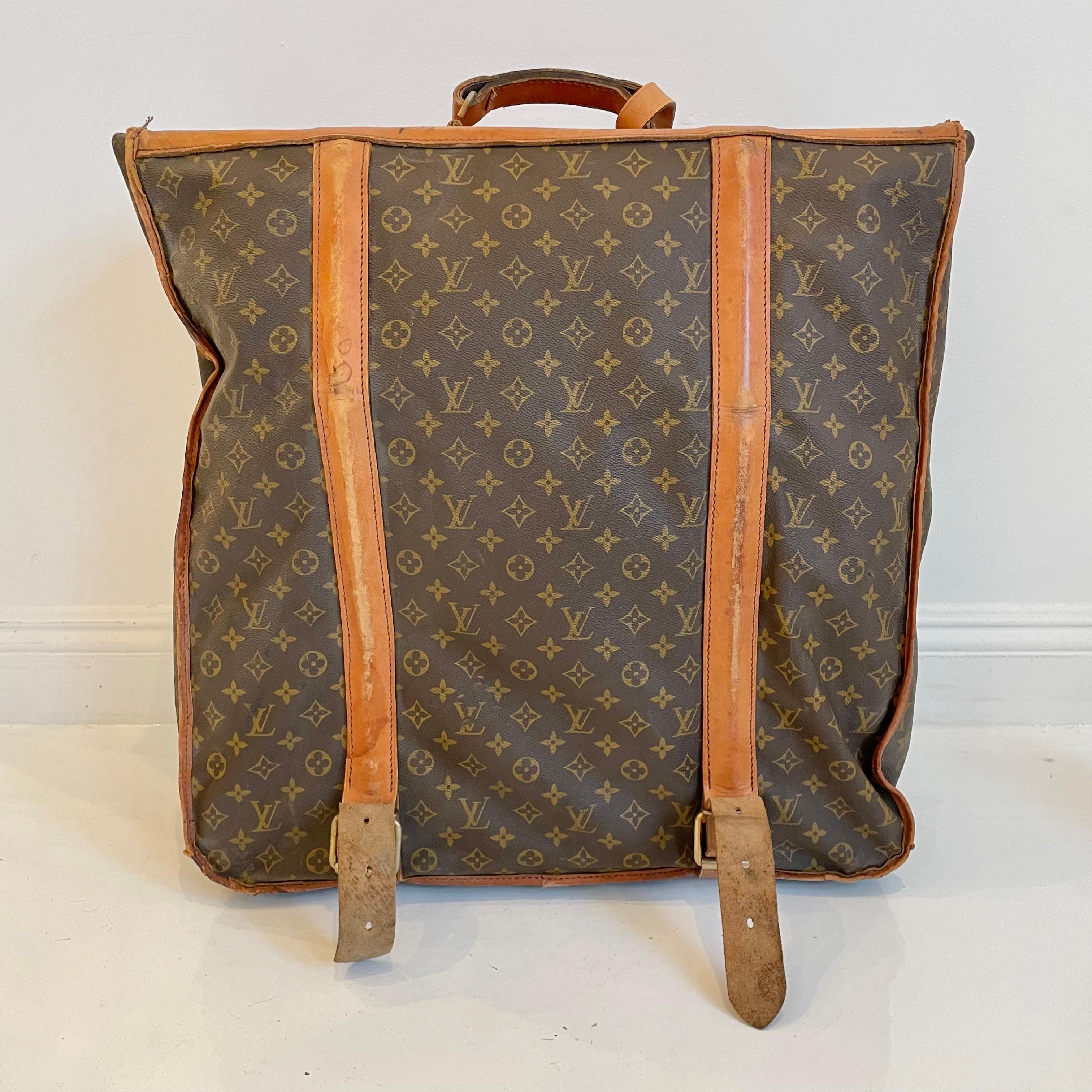 Classic vintage Louis Vuitton garment bag. Oversized bag can fit 7-10 dresses, jackets or suits. Conveniently folds open and closes, secured with leather straps. Perfect for short trips. Timeless LV monogram print with saddle leather and brass