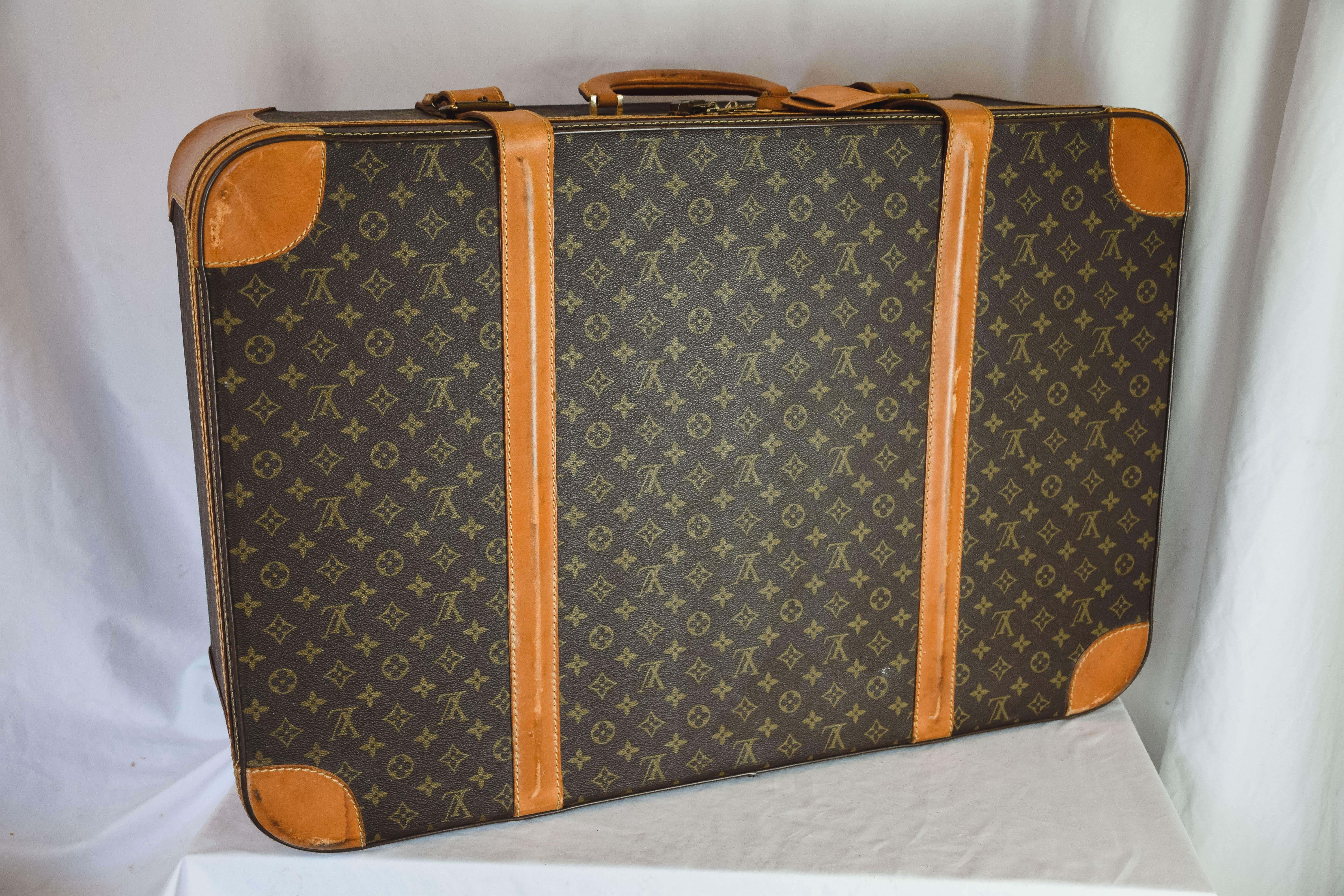A vintage Louis Vuitton brown and beige leather and canvas monogram hold all luggage. This beautiful luggage features a round top handle and buckle fastenings. The inside is in good condition and has two side pockets and also a buckle