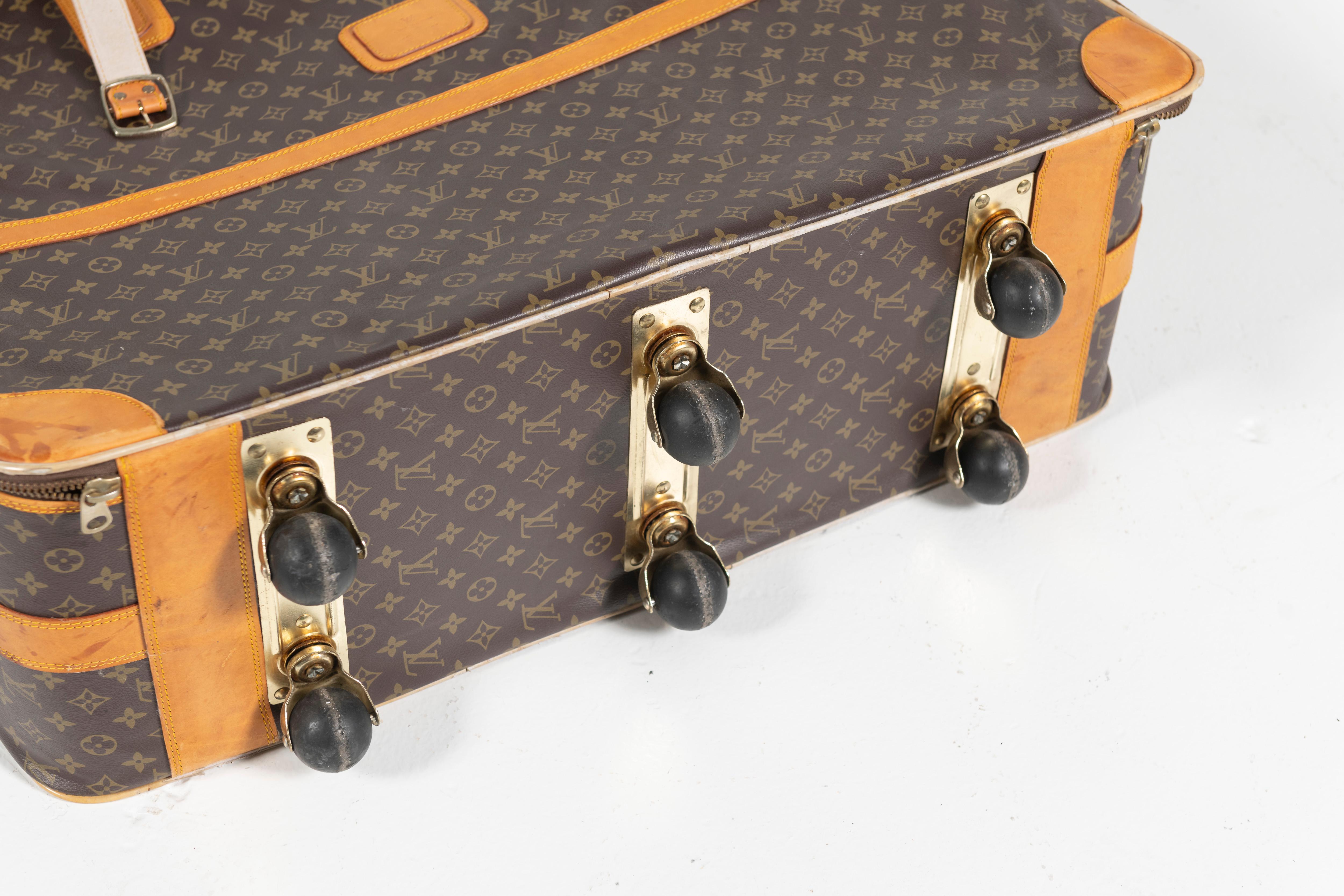 Vintage classic Louis Vuitton soft side suitcase with leather trims, zipper closure and wheels for easy transport. Open interior for you to pack as you like. Large-sized. 