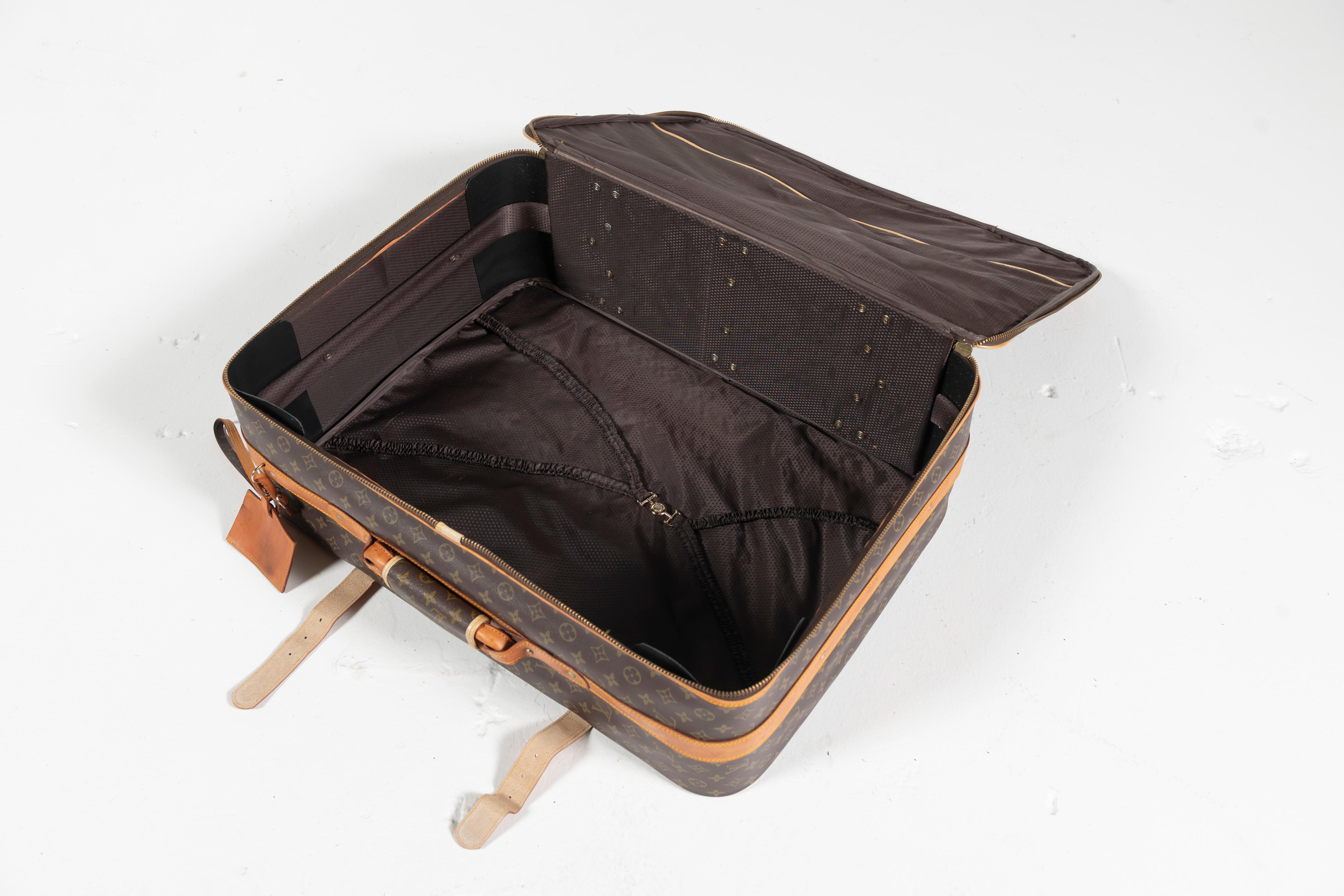 Vintage classic Louis Vuitton soft side suitcase with leather trims, zipper closure and wheels for easy transport. Open interior for you to pack as you like. Medium sized. 