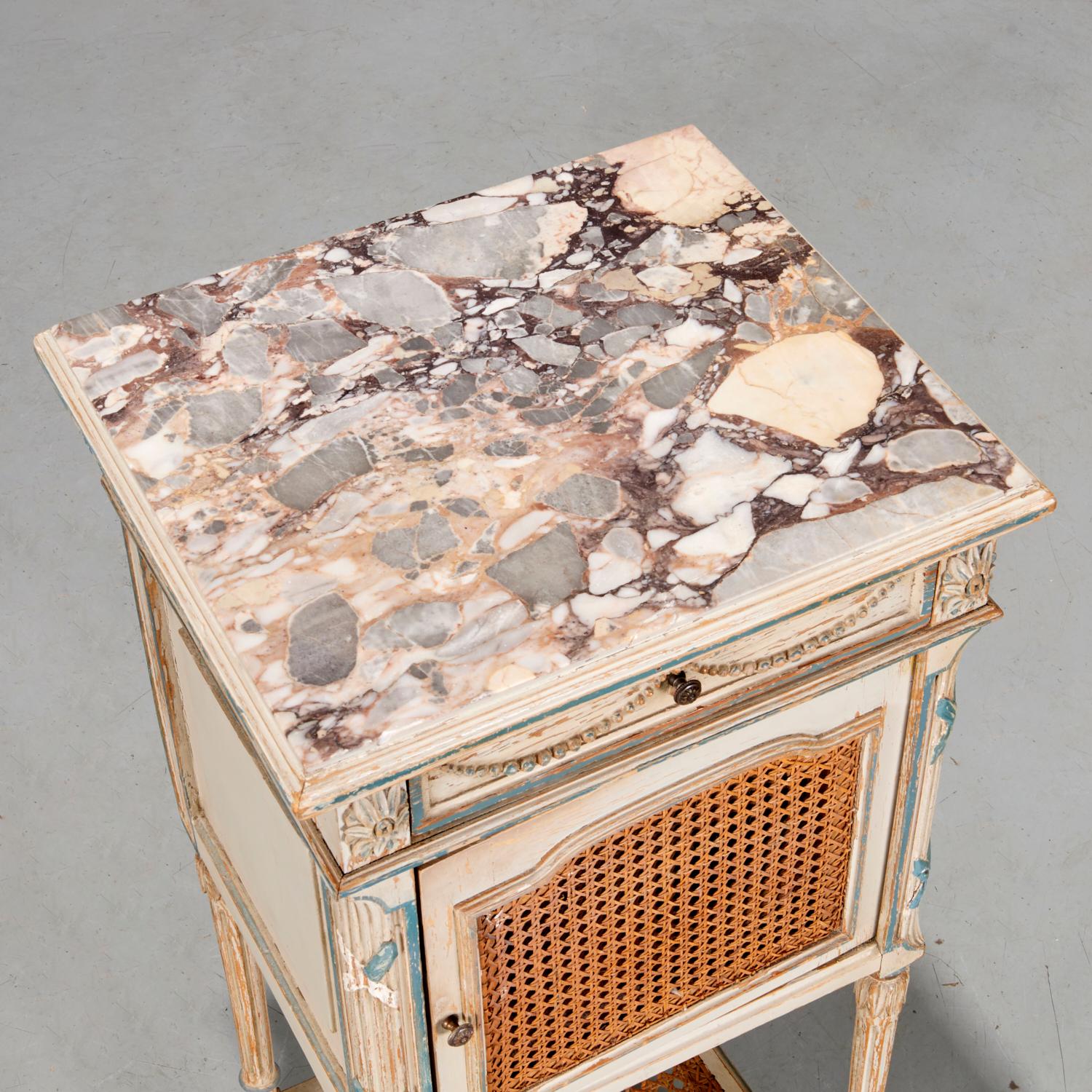 First half 20th c., Italian Calacatta Viola marble top inset in a painted wood nightstand cabinet, with drawer above a caned door front cabinet on fluted legs and lower shelf. The piece is painted in a distressed chalky greige with ribbon accents