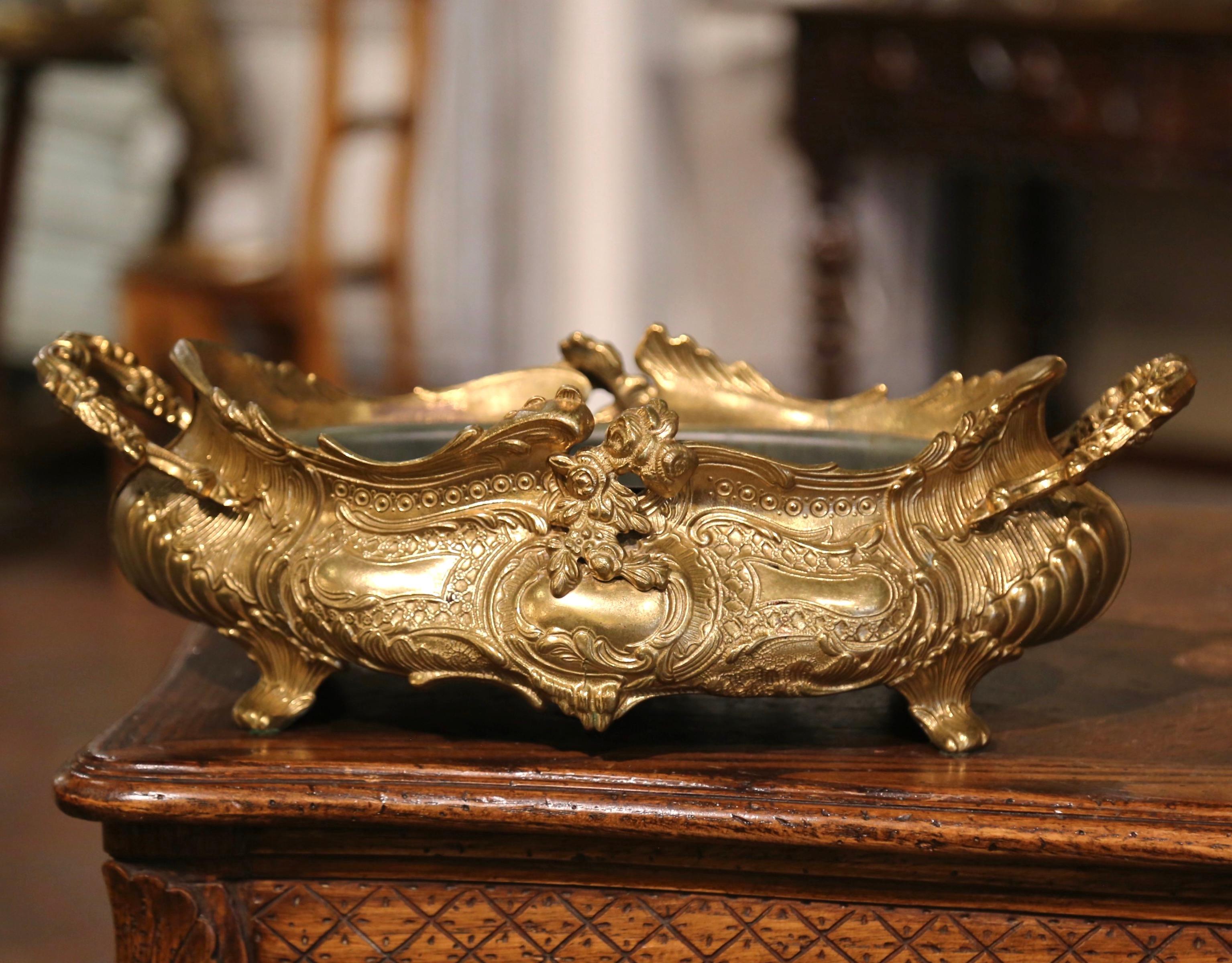 This elegant bronze jardinière with repousse motifs was created in Italy, circa 1990. The oblong vintage planter dressed with side handles, sits on small curved feet decorated with acanthus leaf motifs, over a scalloped apron embellished with shell
