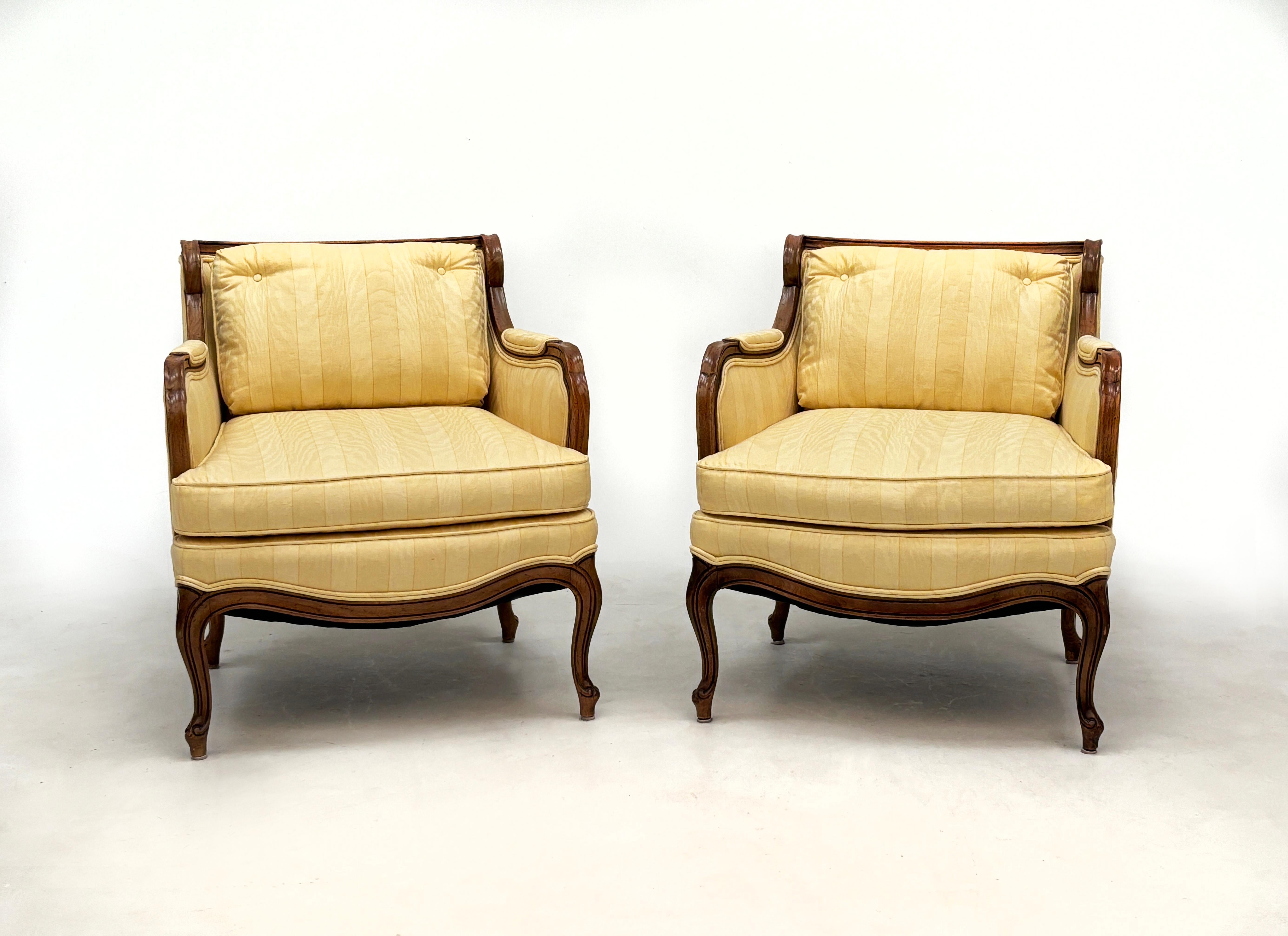 This matching pair of vintage Louis XV-style chairs are delightfully charming with their butter yellow stripe and blind bark textured enclosed upholstery, exposed solid walnut wooden frame with rich and unique natural markings, loose, tailored seat