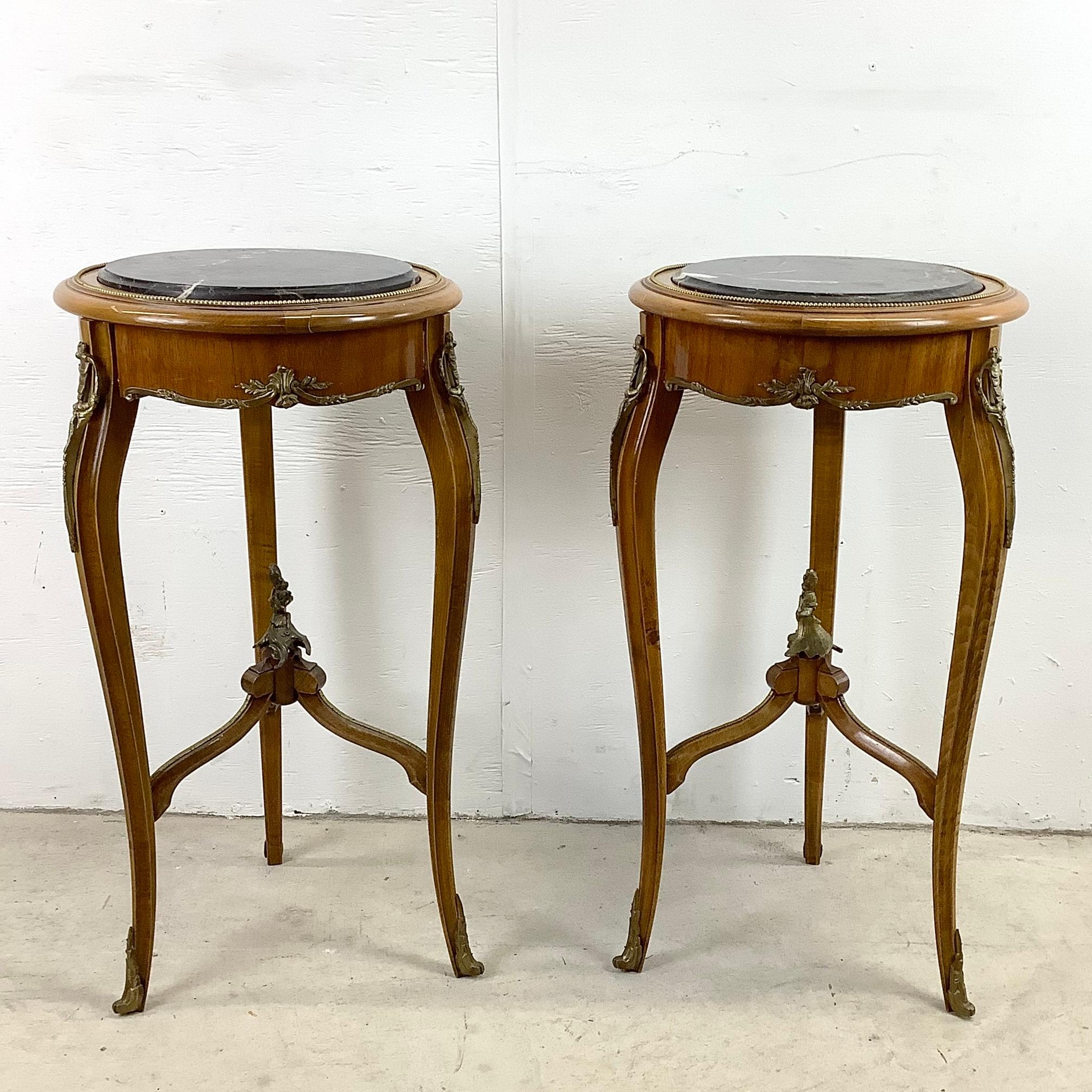 This unique pair of vintage French Louis XV style end tables feature ornate tapered legs with ornate brass finish finial and marbelized black stone table tops. Perfect accent tables for use a display pedestals, lamp stands, or plant stands. Unique