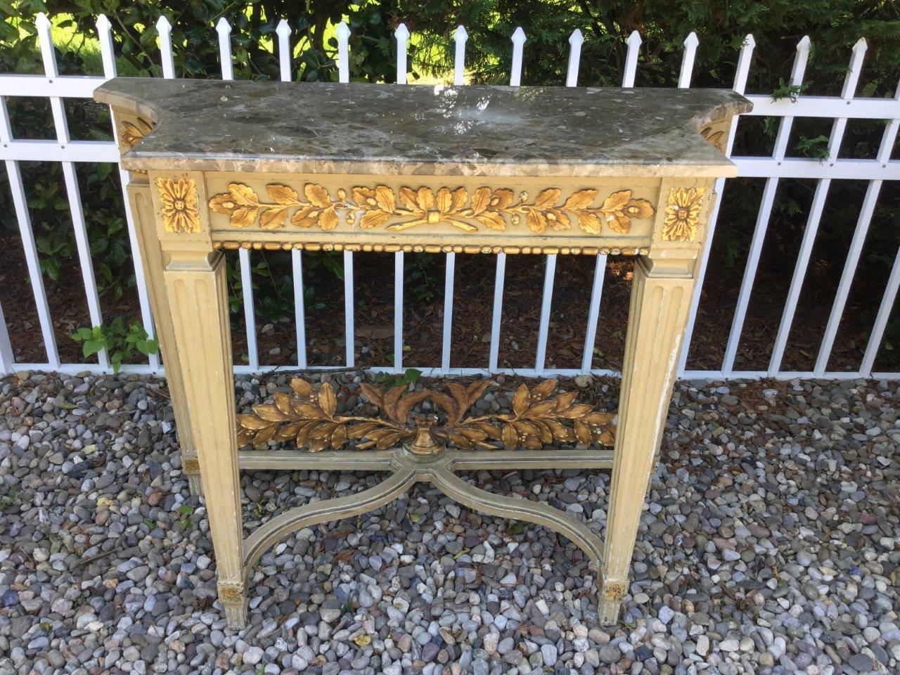Gorgeous Louis XVI style console having a grey and white marble top over painted base enhanced with gold acanthus leaves on all three sides. There is a cross stretcher at the bottom also adorned with gold acanthus leaves. The sides of the console