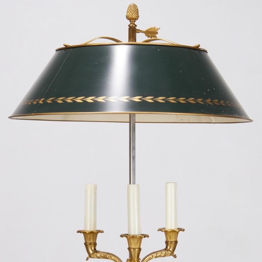 Milieu du XXe siècle, France, lampe de table bouillotte à trois lumières de style Louis XVI, inspirée d'une icône de l'antiquité française. La lampe en bronze doré a un abat-jour en tôle verte réglable par une poignée en laiton doré en forme de