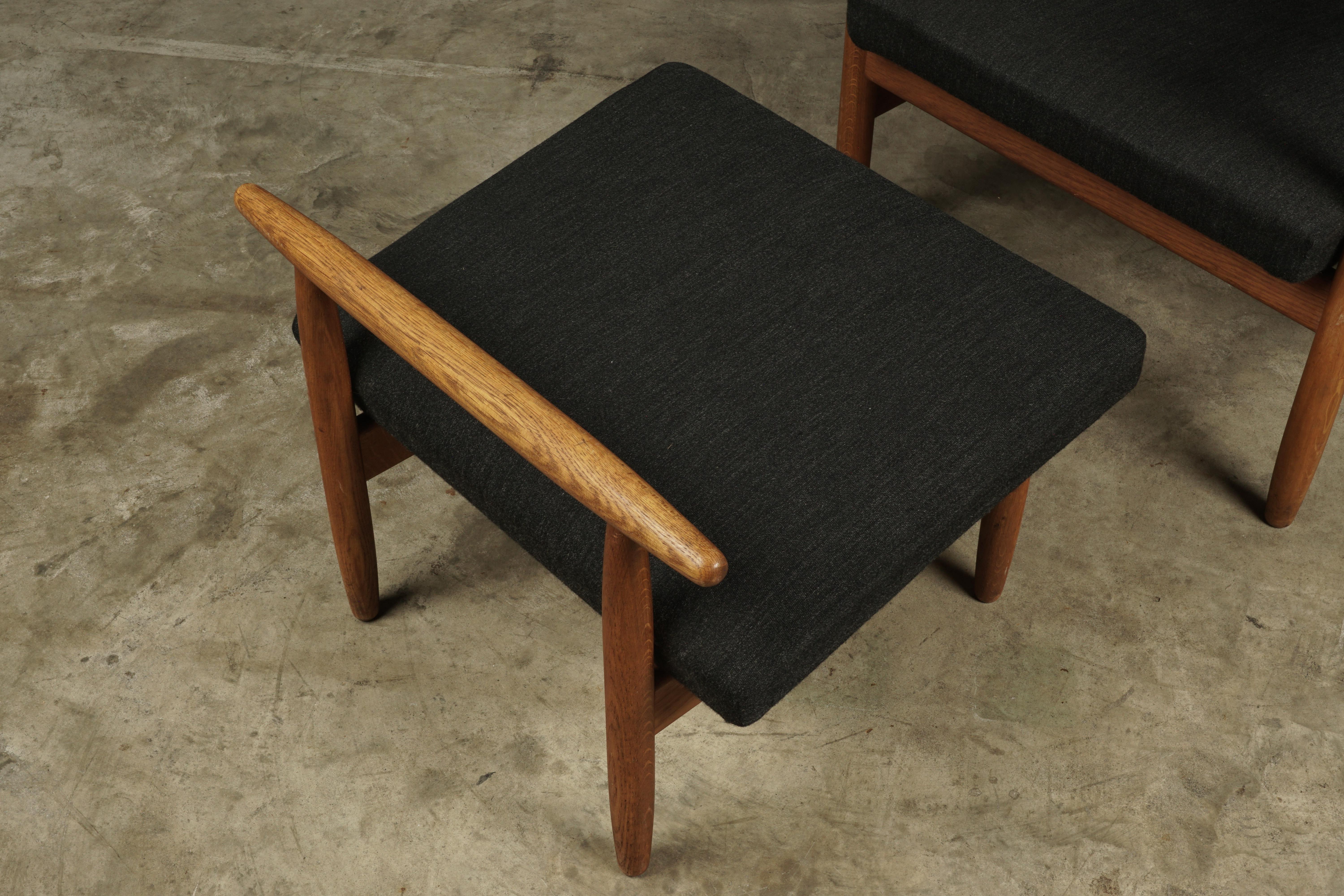 Vintage lounge chair and ottoman designed by Elvind Johansson, Denmark, 1960s. Solid oak construction upholstered in a charcoal grey fabric. Light wear and patina. 

Measures: Ottoman H 17, W 22, D 19.