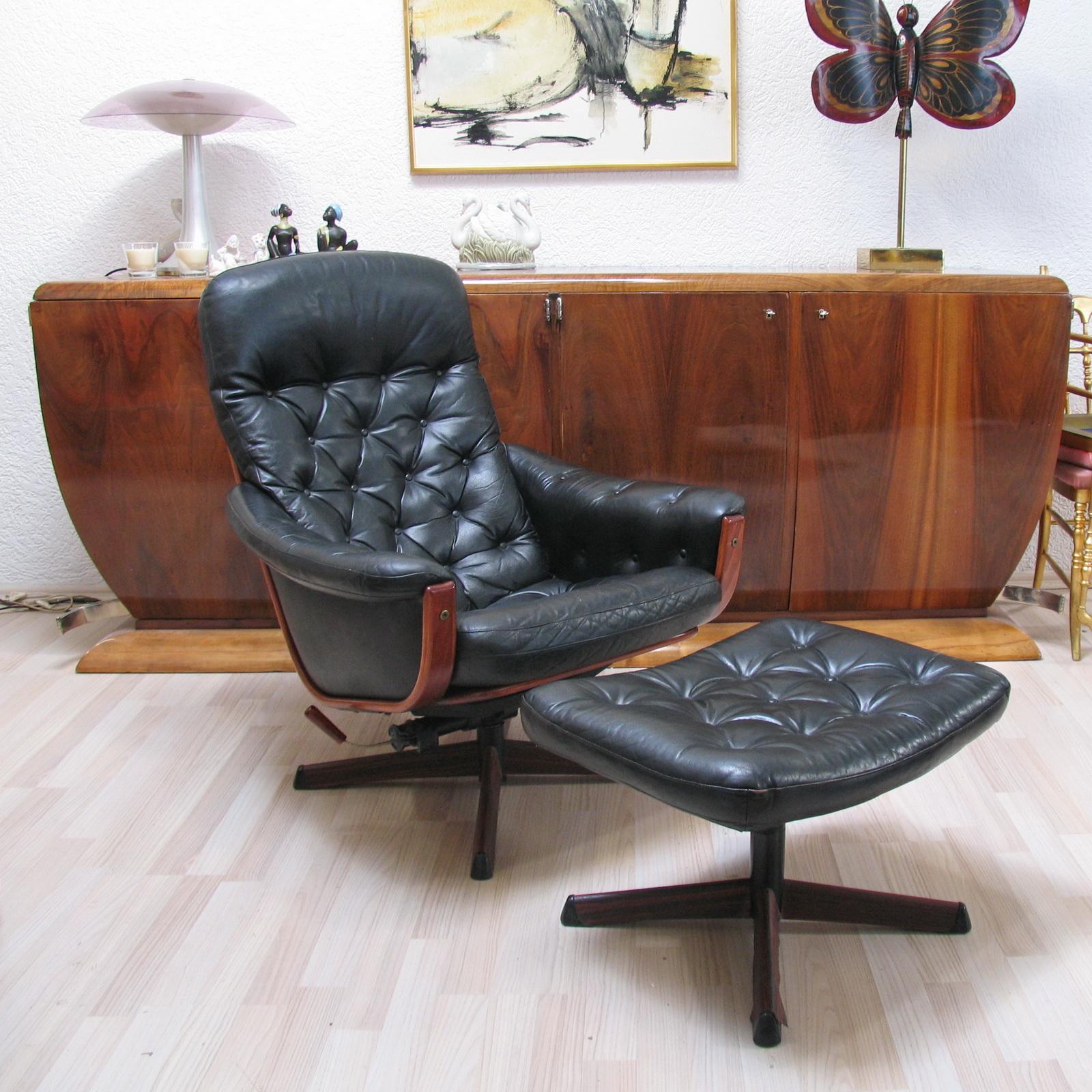 Very comfortable swivel armchair with its matching footrest, by Göte Möbel Nassjo from Sweden with adjustable backrest. Curved wooden frame with black leather padded upholstery. Metal star base with a wood pattern application. 
Good overall