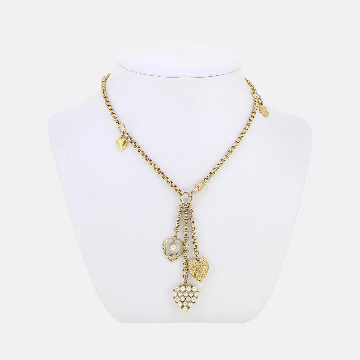 Here we have a vintage 9ct yellow gold belcher chain charm necklace. The necklace plays host to a three freely hanging love heart pendants. One heart plays host to a single natural pearl amidst an open pierced frame. The second is entirely set at
