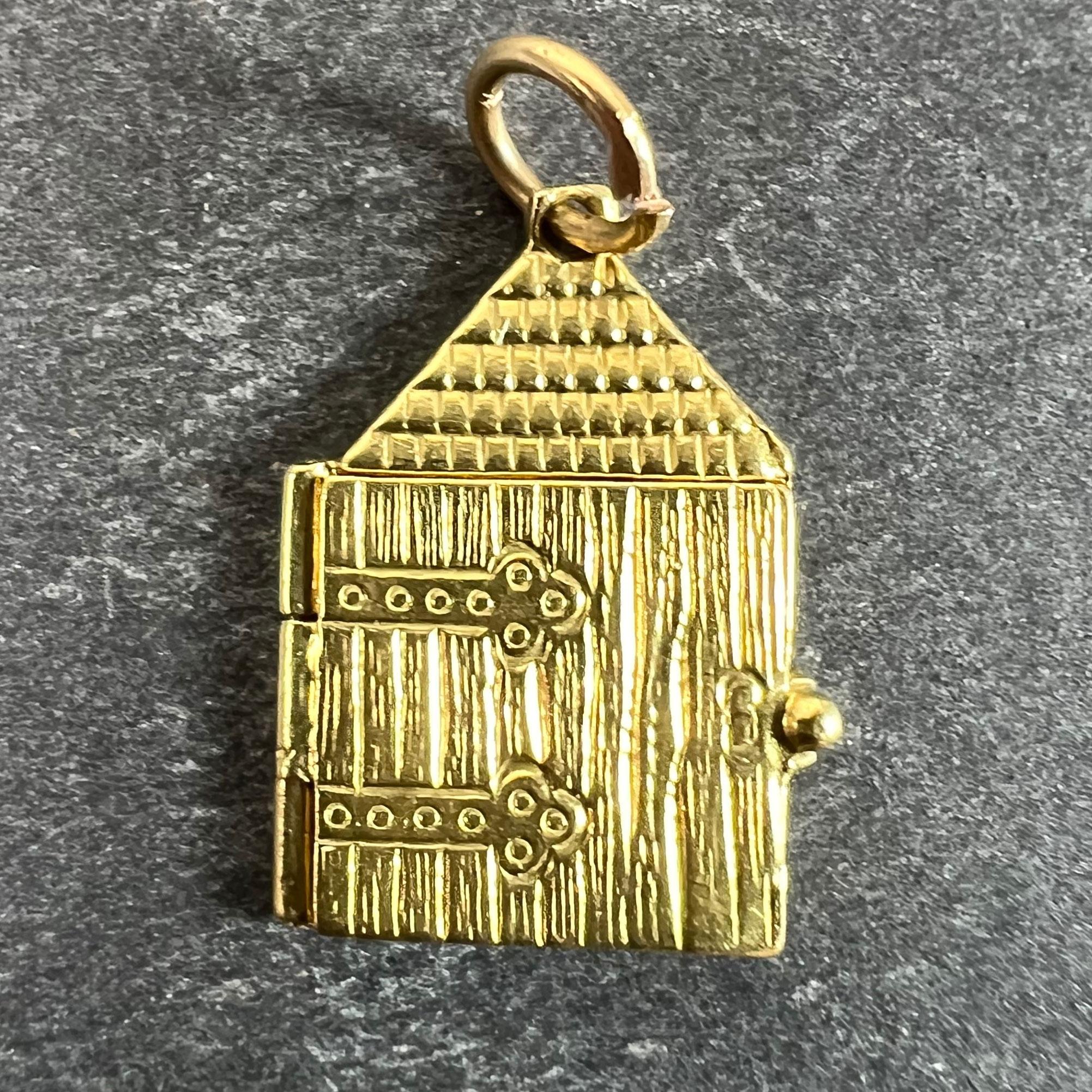 Un ciondolo charm in oro giallo Art Deco 18 carati (18K) disegnato come una casa con una grande porta sul davanti incisa per mostrare un paio di grandi cardini e assi, che si apre per rivelare un cuore d'amore in smalto rosso. Sul retro della porta