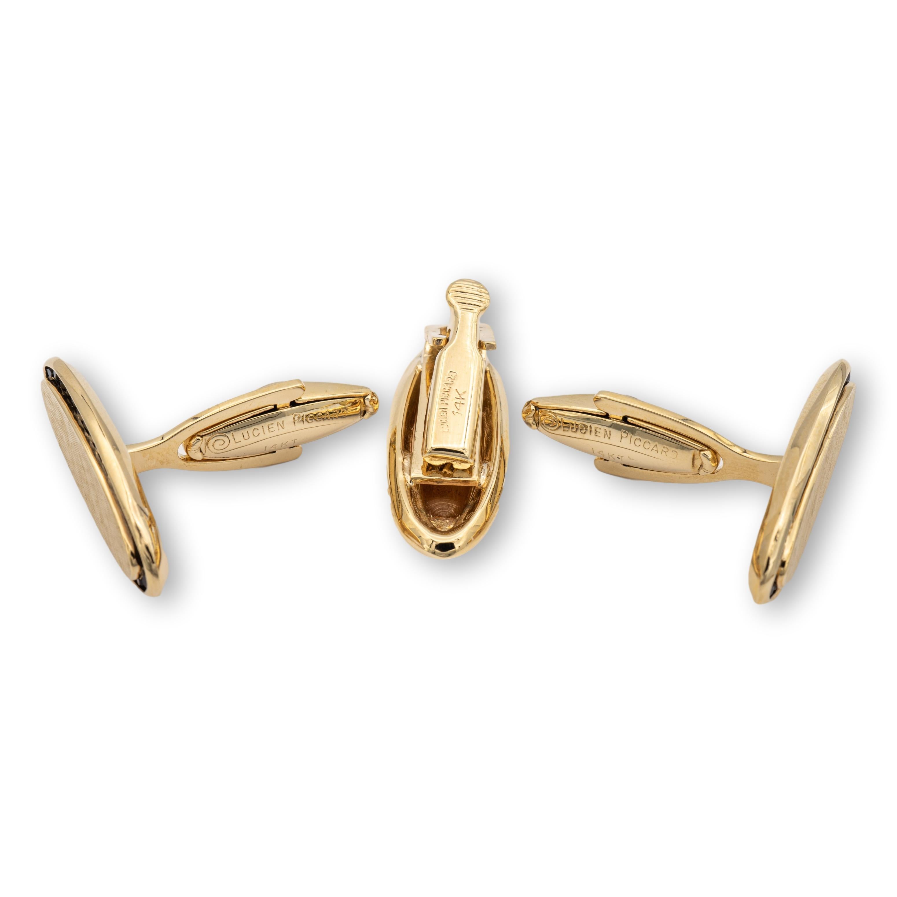 A set of vintage men's cufflinks and tie clip by famous watchmaker Lucien Piccard finely crafted in 14 karat yellow gold each featuring a rim of channel set garnets in an elongated oval face with a satin finish in the center and whale backs. The tie