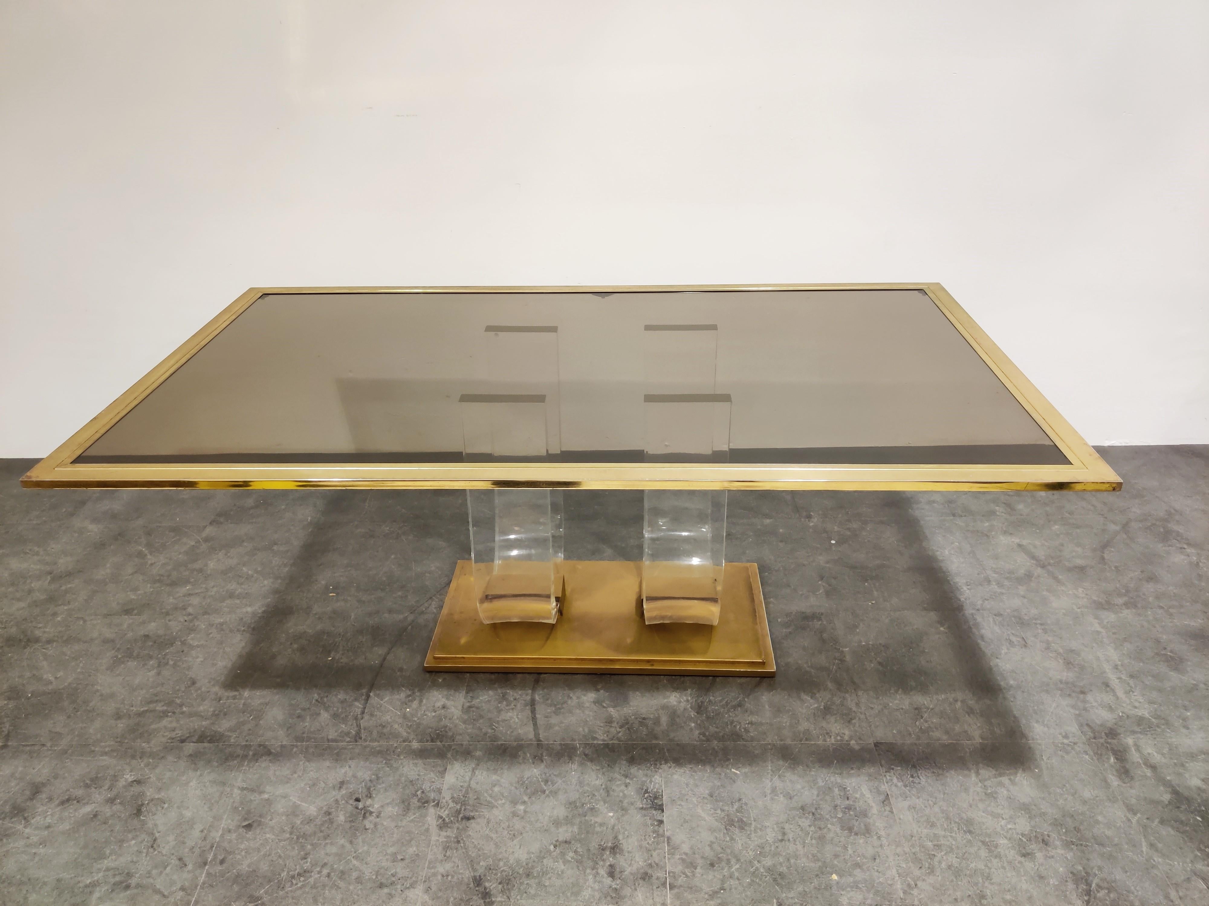 Beautiful Hollywood Regency dining table.

Rectangular brass frame and smoked glass top mounted on a double arched Lucite base with a solid brass foot.

Spectacular design which will be a real eye catcher for the dining room.

Timeless