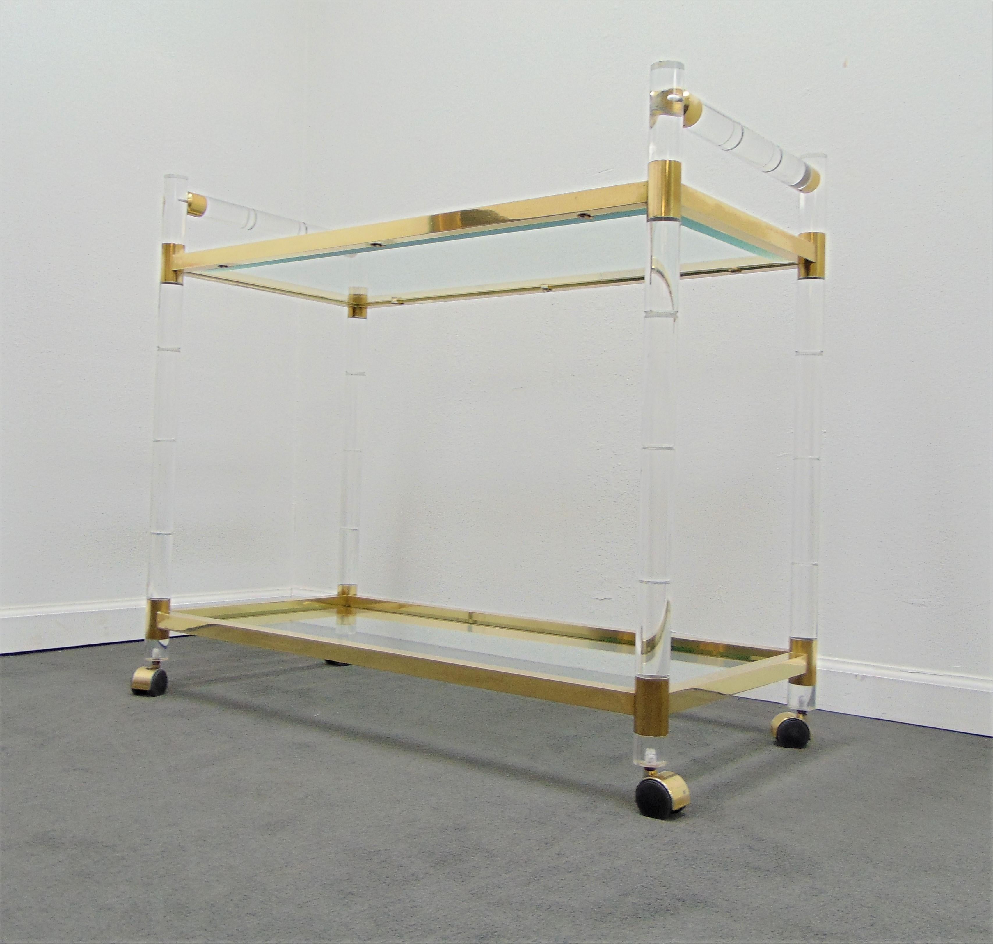 This bar cart is a wonderful example of Hollywood Regency midcentury style. This bamboo styled Lucite bar cart has a brass frame and beveled glass shelves. This bar cart was designed by Charles Hollis Jones.