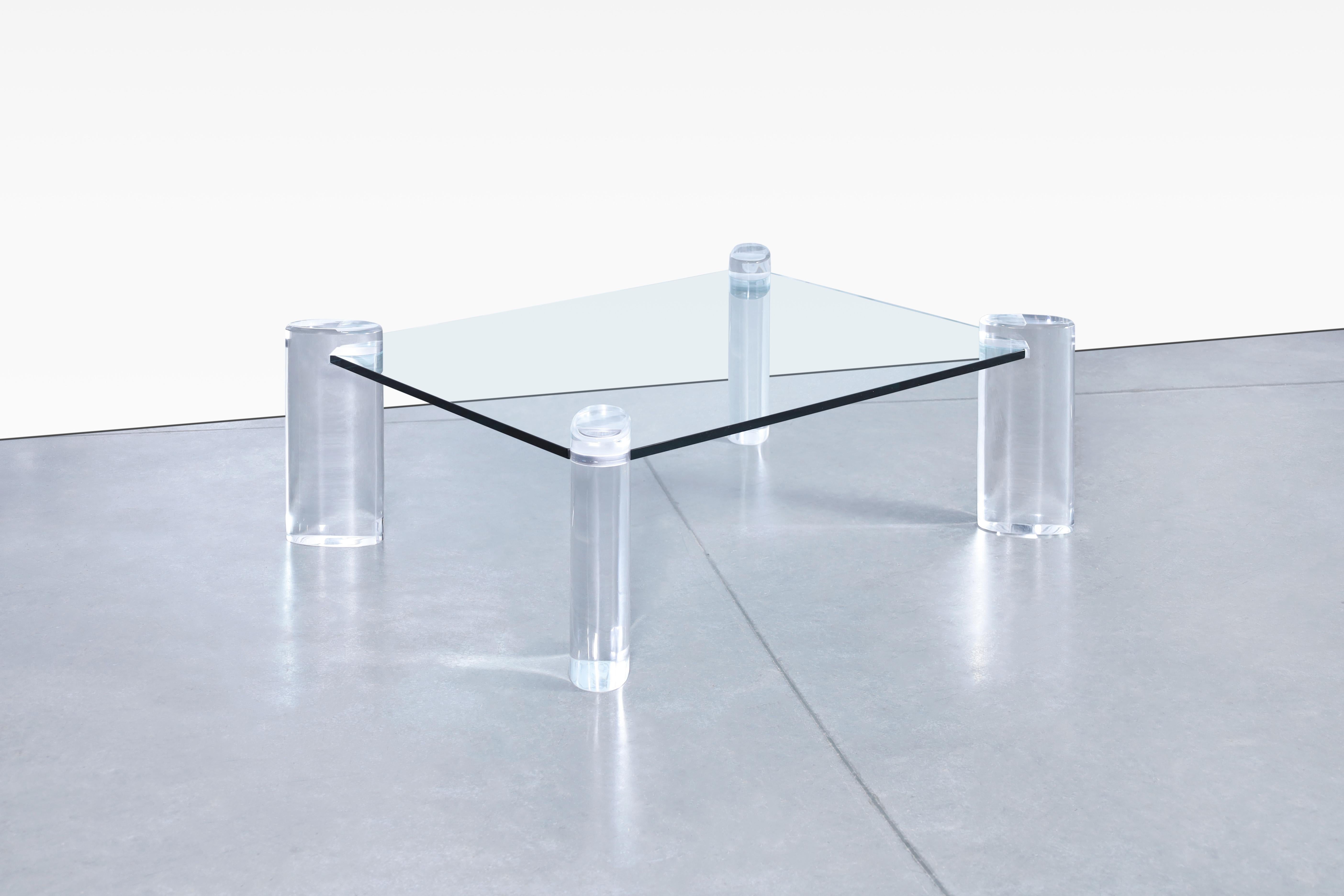 Wonderful vintage lucite and glass coffee table designed by the iconic designer Karl Springer in the United States, circa 1980s. This coffee table has a unique design in which its construction materials and the shape of its design stand out. Created