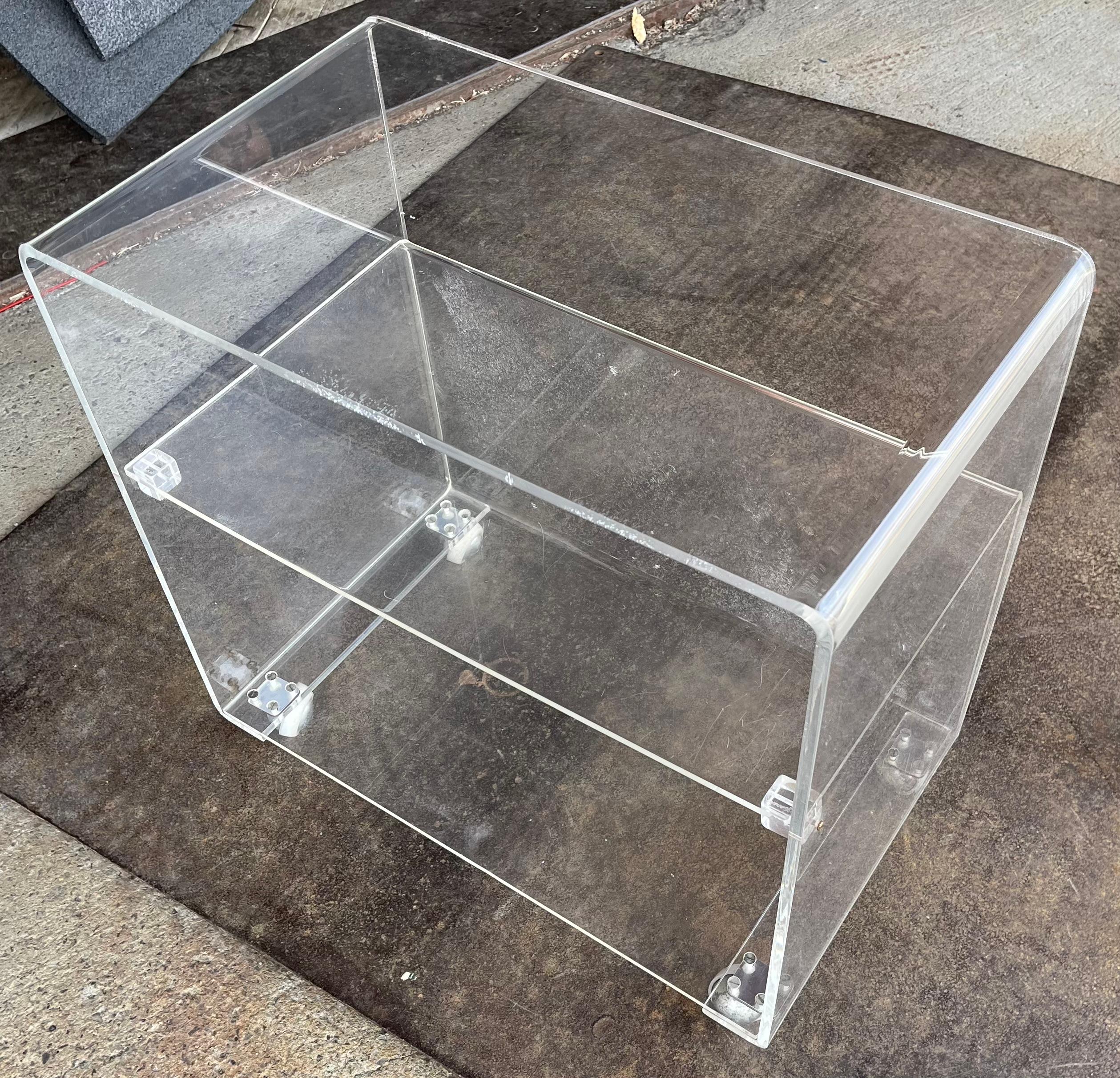 Chic  Post Modern, Space Age, Hollywood Regency rolling bar, service cart, executed in solid lucite. The cart features three shelves,  the lower two shelves have a closed back, the whole encased in a waterfall form shell. 
 This example is in very