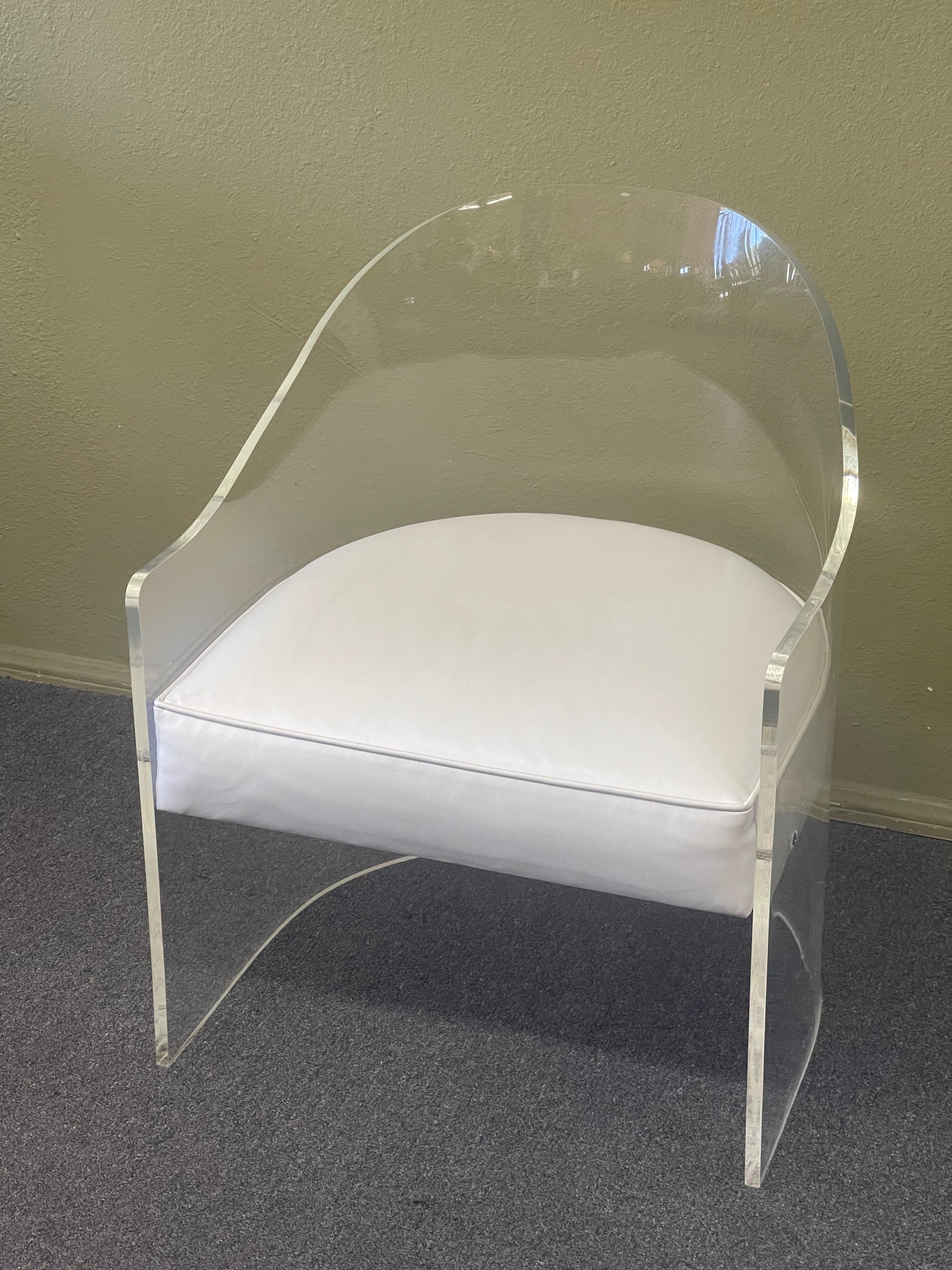 Stylish lucite barrel chair with white naugahyde seat, circa 1970s. The chair is in very good vintage condition with some minor scuffing and scratches around the base; it measures 22.75