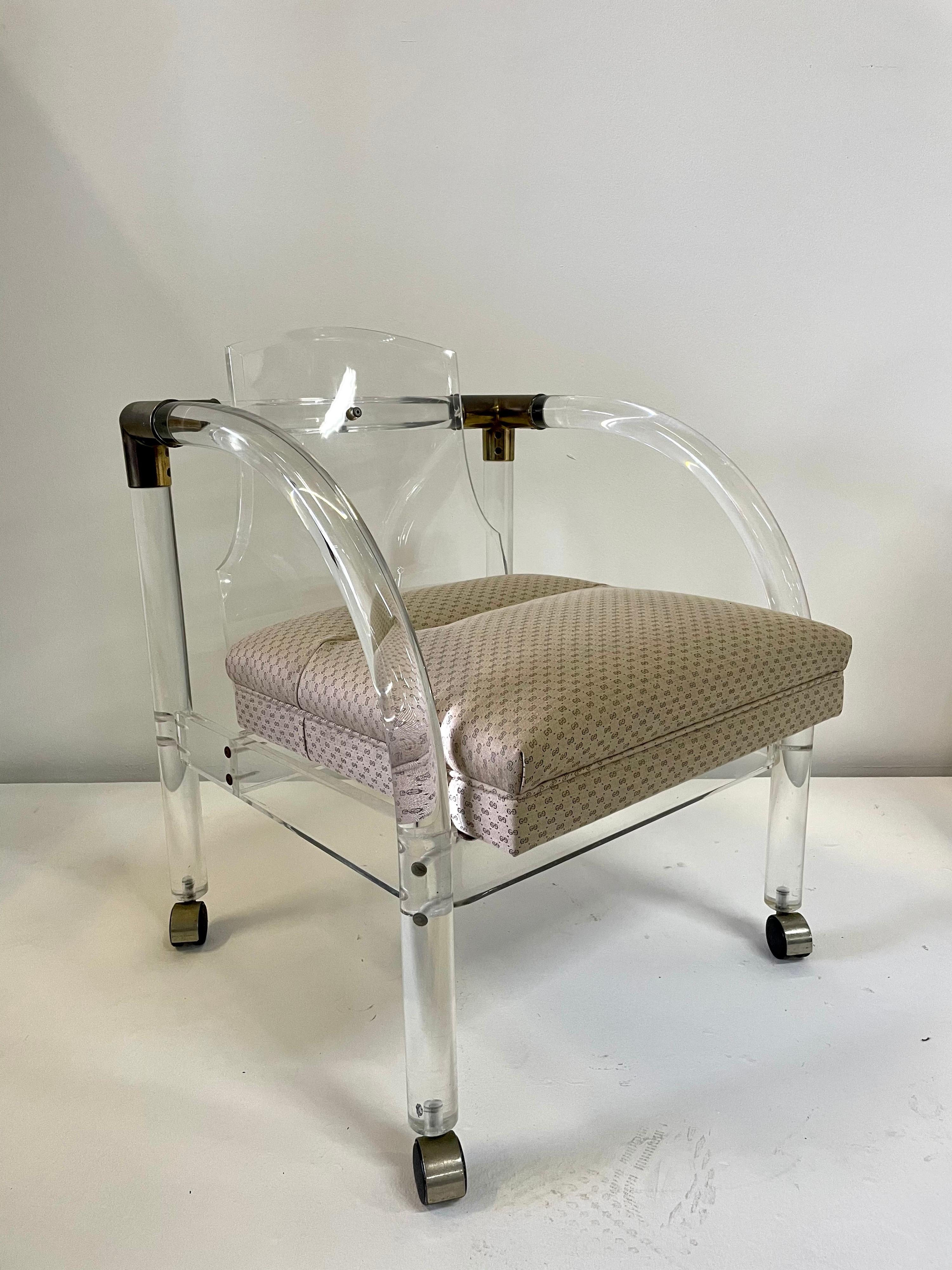 This is a great Lucite armchair with brass corner accents. The chair is on casters/wheels for easy movement. The fabric on the seat is a commercial grade vintage Gucci fabric.