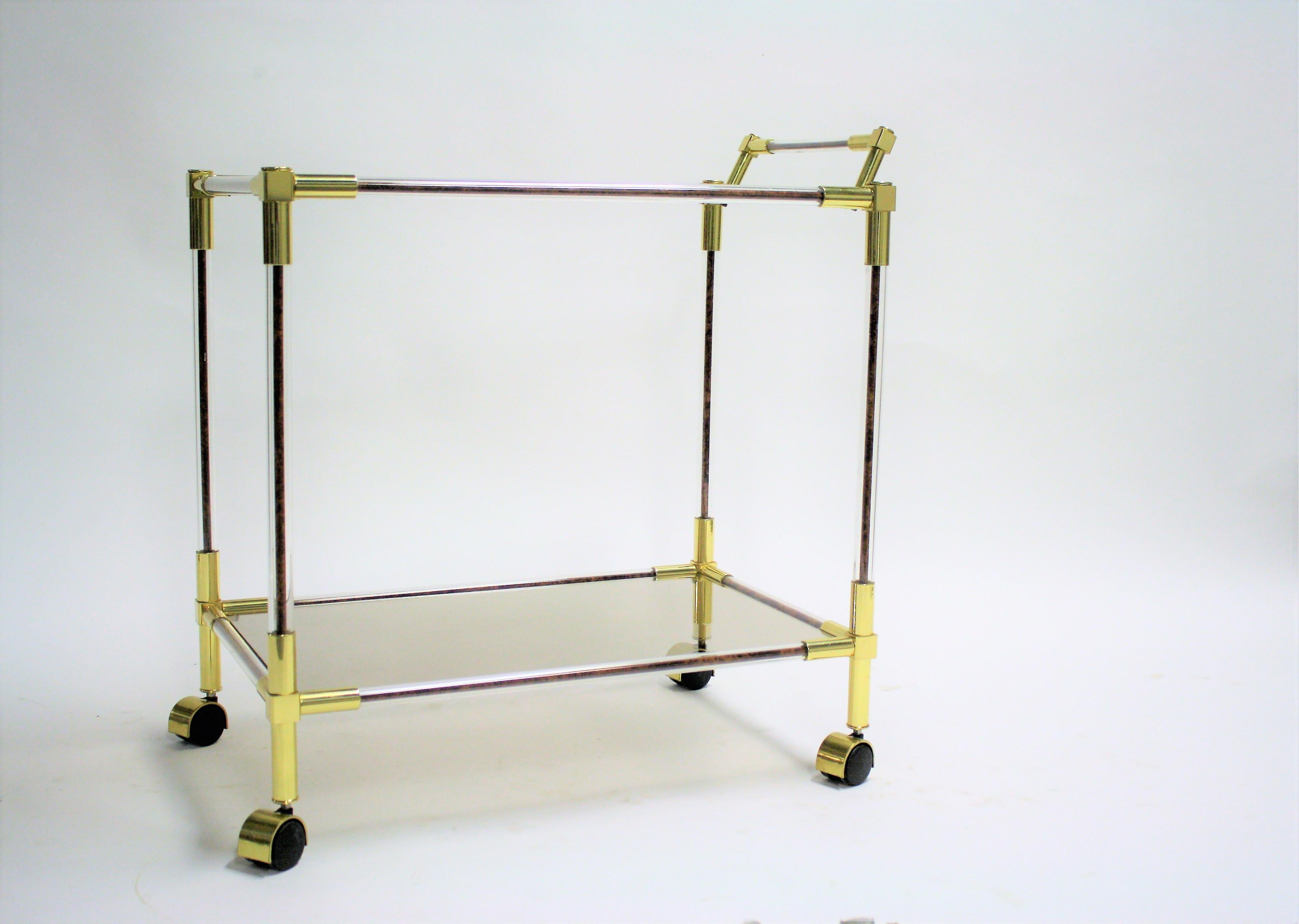 A Hollywood Regency two-tier dessert trolley.

The trolley has a brass and Lucite frame with burl wood and smoked glass shelves.

Very good condition.

Beautiful trolley to present plates, drinks or even to use in a shop for other