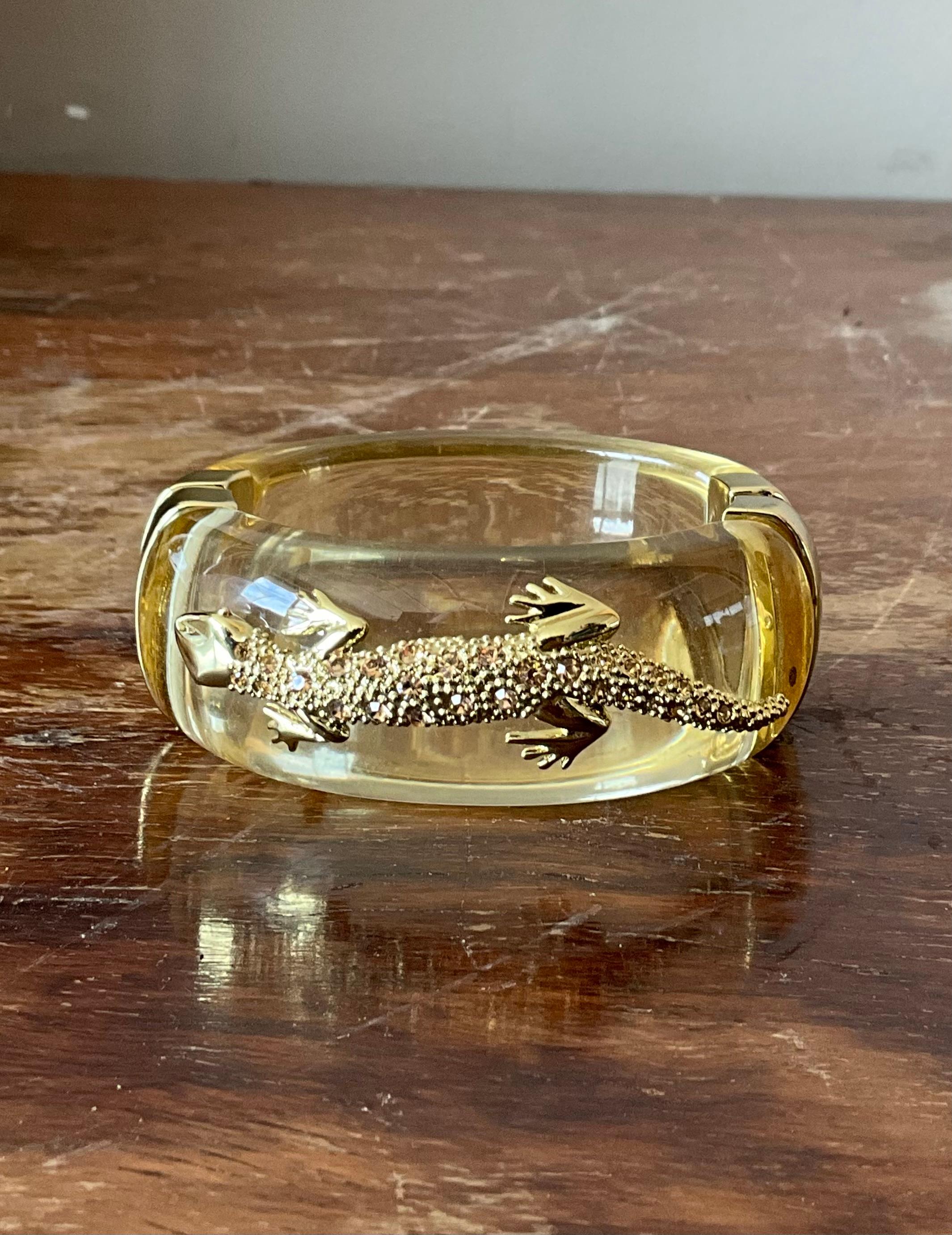 Make a bold statement with this eye-catching vintage Lucite and rhinestone-encrusted lizard hinge bracelet. Designed to captivate, this unique piece features a sleek, sculpted lizard wrapping gracefully around the wrist, shimmering with meticulously