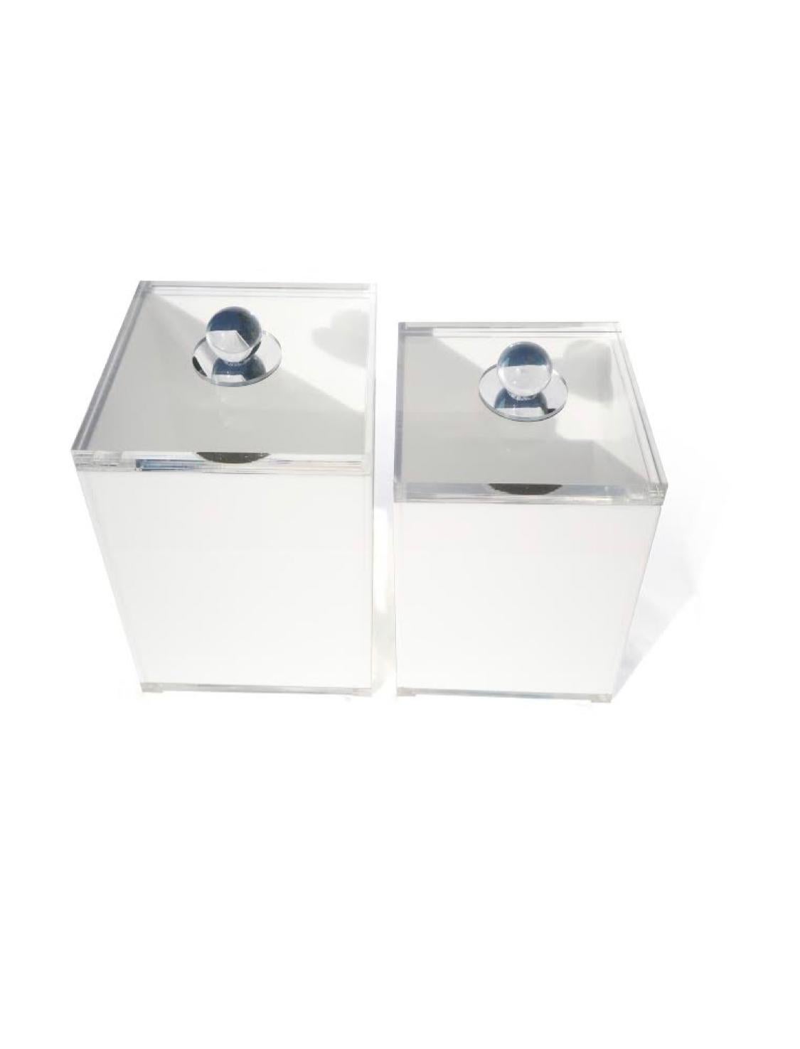 An elegant set of four vintage Lucite storage containers. Each has a white canister on a clear base and feet. Lids are a thick piece of clear Lucite with a round handle on a mirrored disc. 

Perfect for any modern kitchen, or Mid-Century Modern