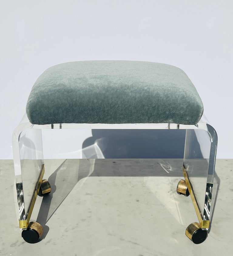Mid-Century Modern lucite vanity stool with curved waterfall frame. Newly upholstered in La Maison Pierre Frey's luxurious Teddy Mohair, color celadon which sells for $500 per yard. 
This stool features chic brass banded accents along the bottom of