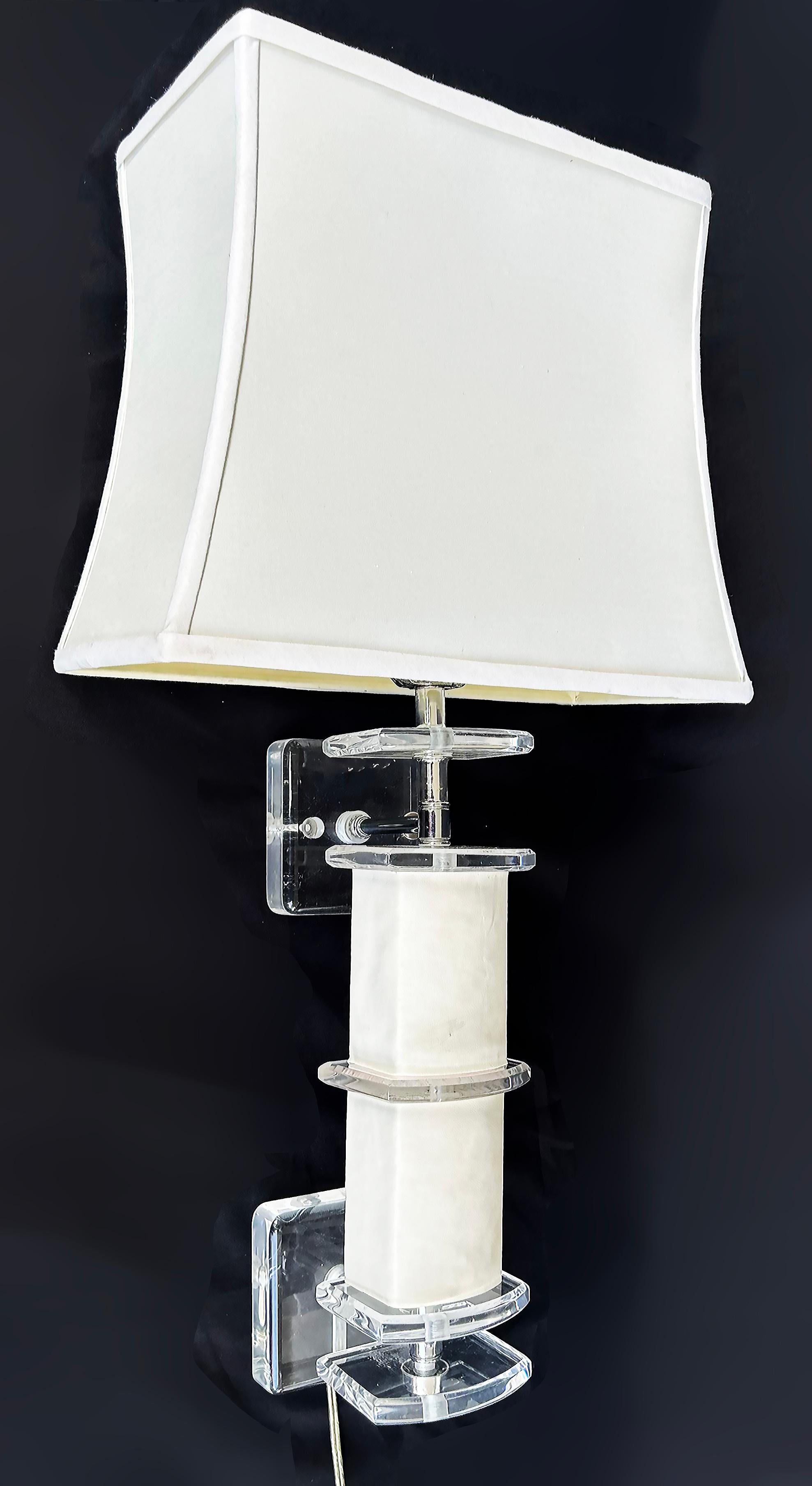 Vintage Lucite Wall Sconces with Faux Leather, Lucite Finials, and Lampshades

Offered for sale is a pair of vintage Lucite wall sconces with their original Lucite finials and shades. The sconces have columns wrapped in faux leather with decorative