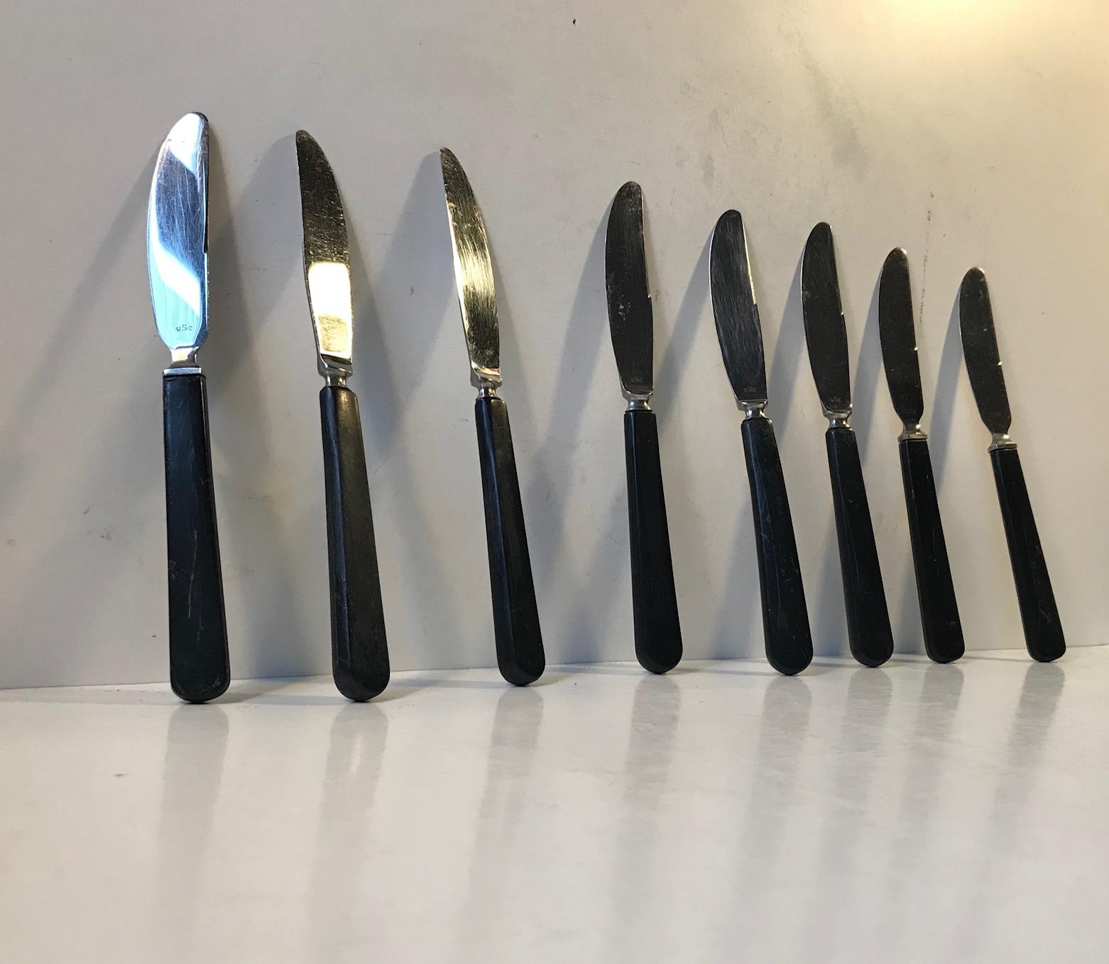 A set of 8 stainless steel and black resin dinner/lunch knives. Designed by Kay Bojesen and manufactured by United Steel Company in Denmark during the 1950s. During this period KB worked as a Artistic Leader at the Company. Each knives are stamped