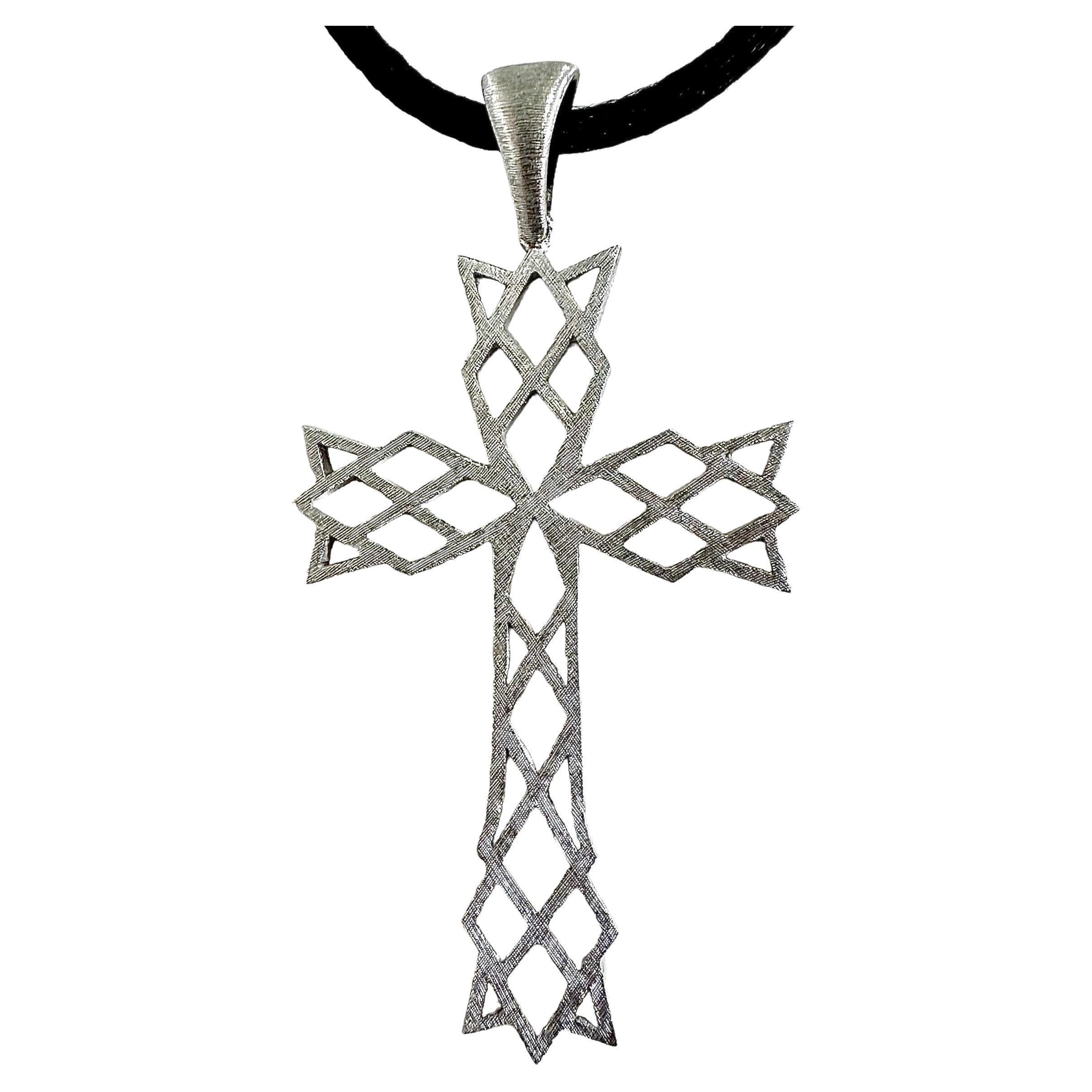 Cette croix vintage très unique et architecturale de M. Bucellatti est réalisée en or blanc 18 carats et est suspendue par un joli cordon rond de 2 mm en satin noir, de la longueur d'un tour de cou. L'embout du cordon et le fermoir à mousqueton sont