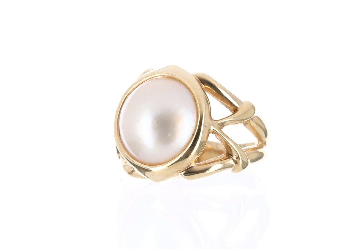 Displayed is a contemporary Mabe pearl and gold solitaire ring. The natural center stone has a beautiful cream color and impressive size. The pearl measures an exact 14.0mm x 14.0mm and is breathtaking. Steadily put, the mabe pearl is held in a