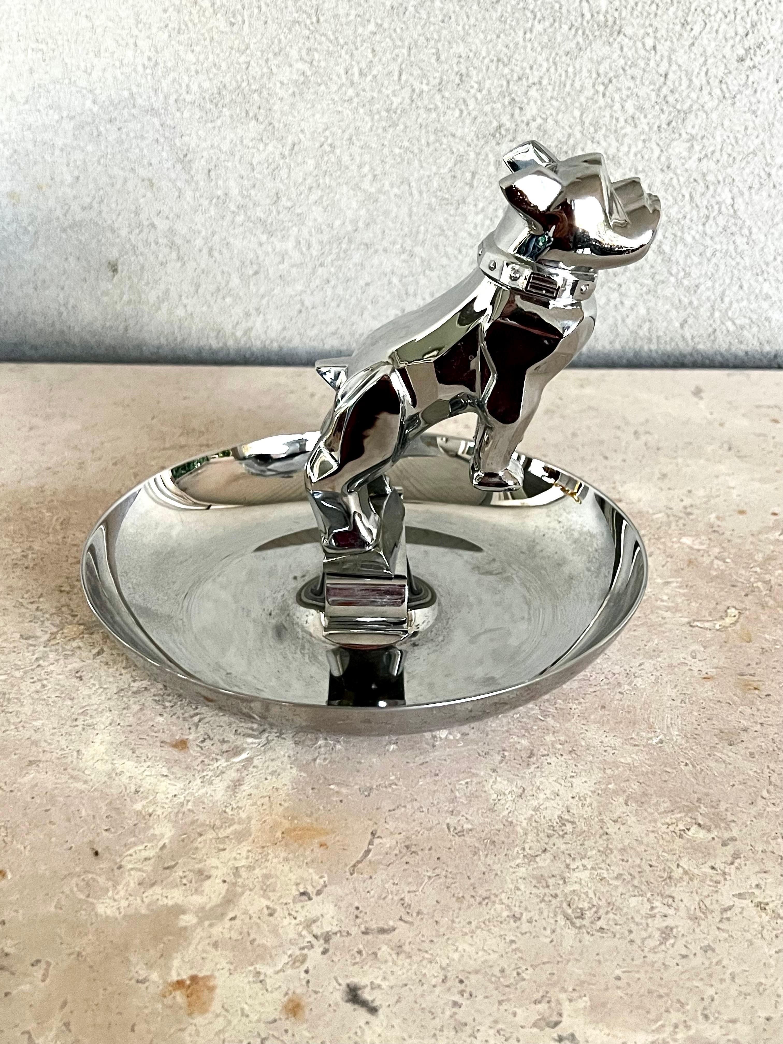 A well-known and popular cigar ashtray, this vintage piece has the classic Mack Truck Bulldog hood ornament , poised on its hind legs at its center. There is a cigar rest on each side of the Bulldog.

The entire piece is made of chrome and it is