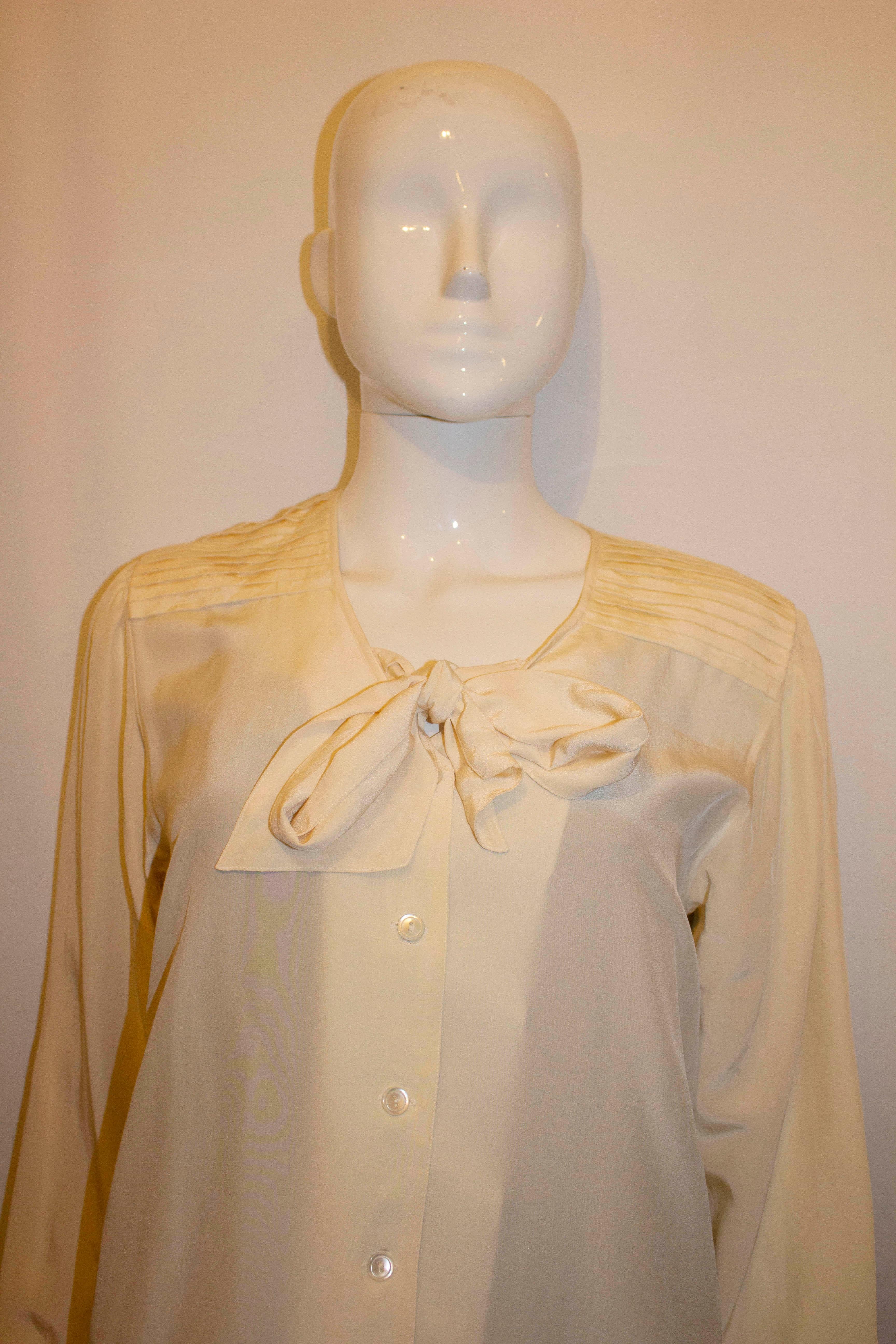 A chic vintage silk blouse by Madame Hanai , the Japanease designer. The blouse is in a super soft silk and has a button front opening with a v neckline and neck ties.  It has a single button cuff and pleats on the shoulder.