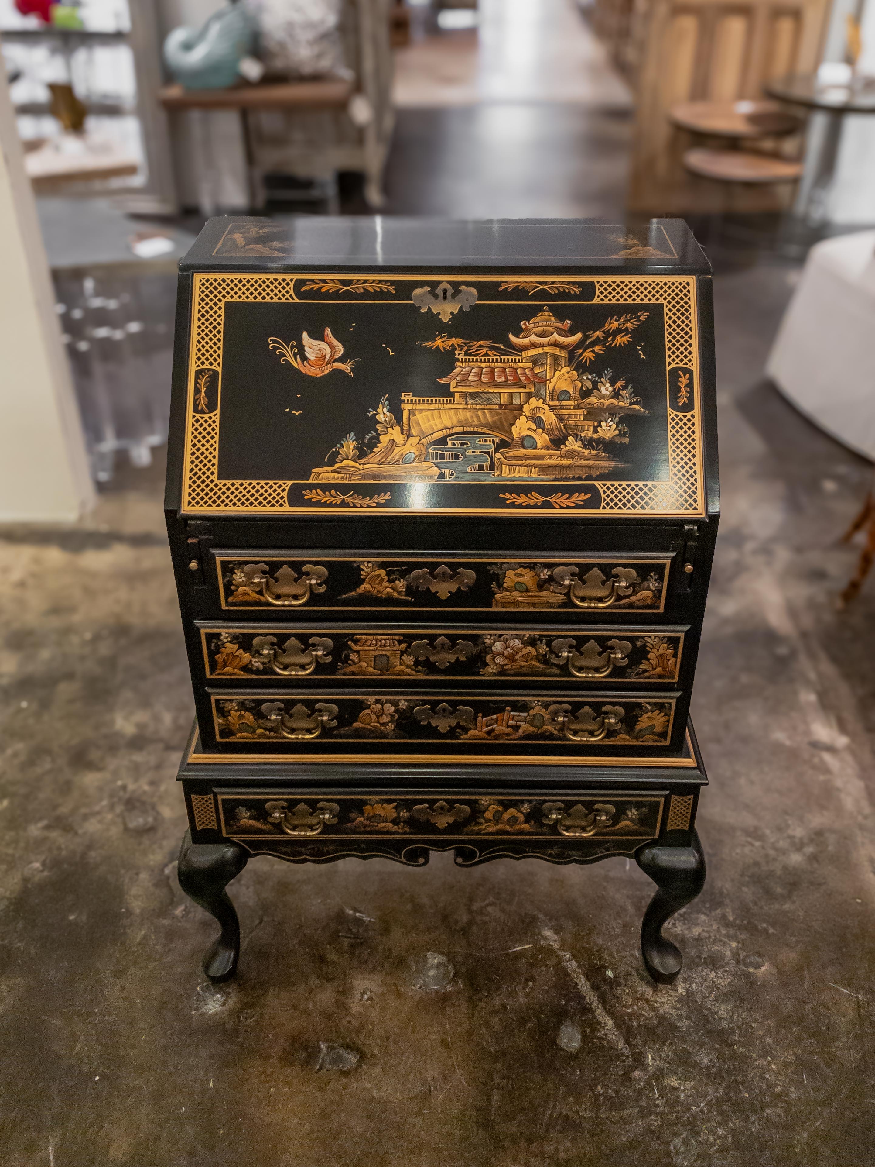 The Vintage Maddox Chinoiserie Black Lacquer Slant-Front Writing Desk is a captivating piece of furniture that blends functionality and artistic allure. This desk, dating back to a bygone era, exudes the charm of Chinoiserie design, inspired by