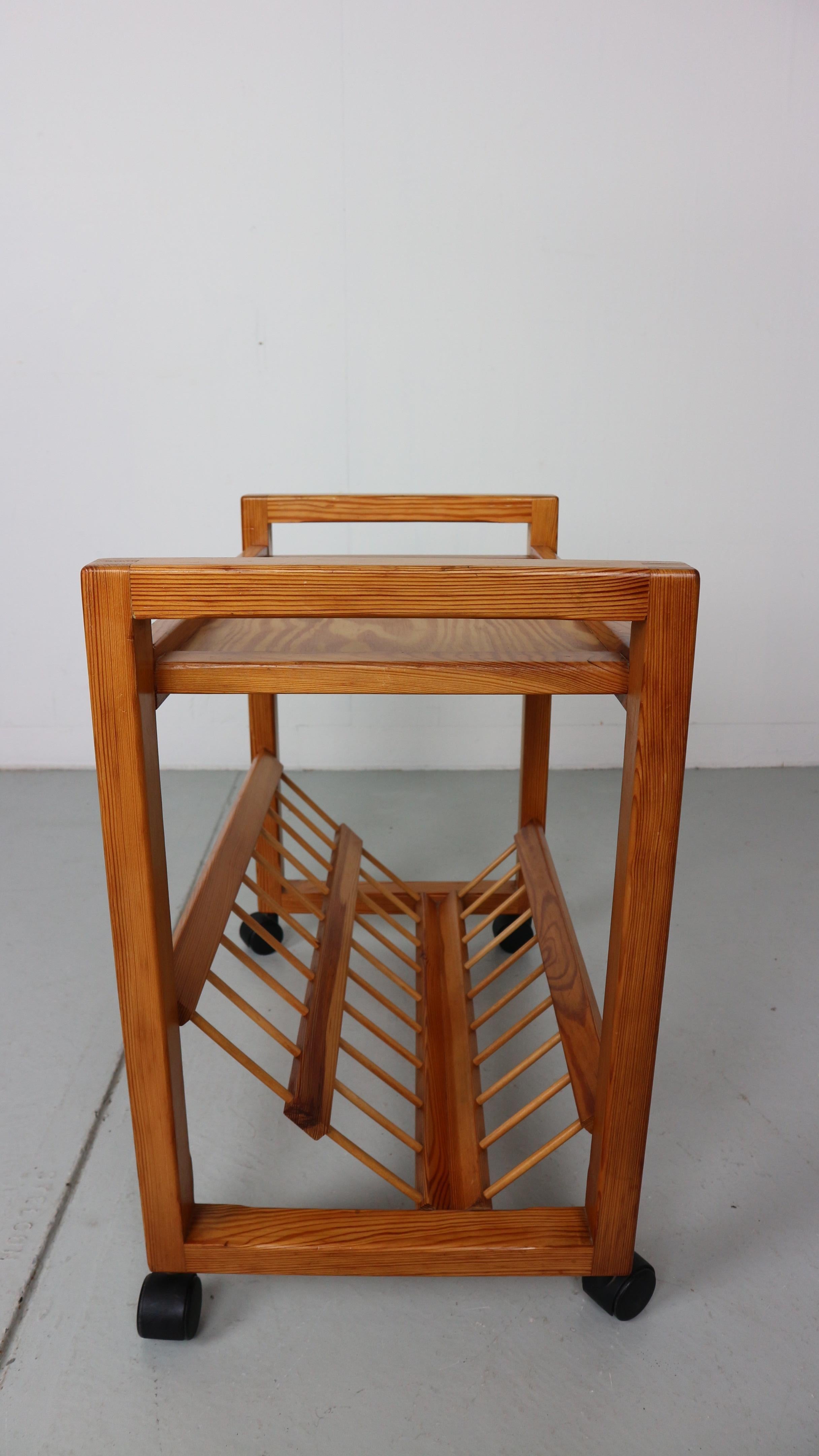beautifully made pine magazine rack with wooden details on black plastic wheels. Can be used as bar card or serving / side table. 
Attributed to Ate van Apeldoorn, a Dutch designer who made lots of furniture mostly in pine.