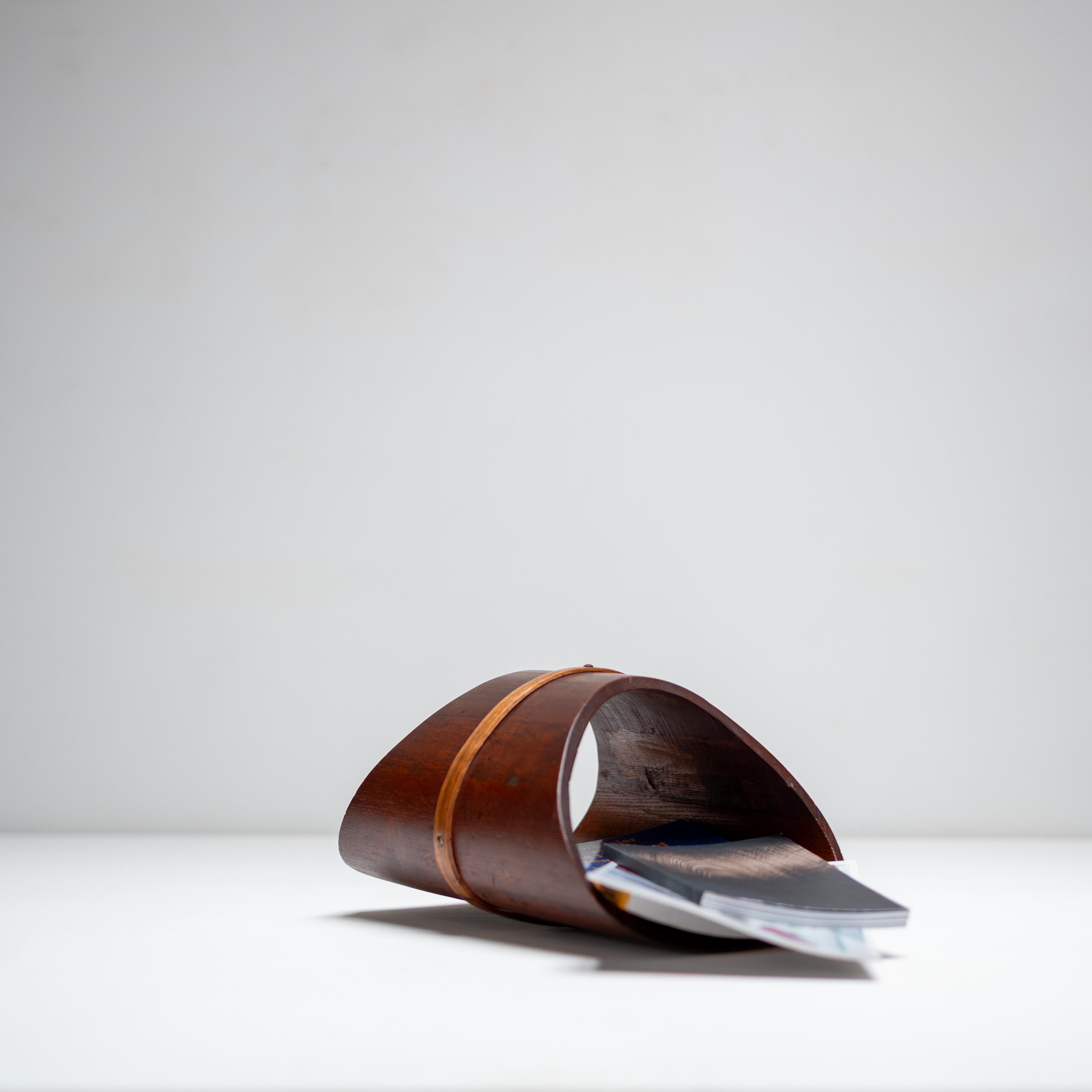 Ein wunderschön gearbeiteter Zeitschriftenständer aus Holz. Dieses skulpturale Stück ist ein Beispiel für den minimalistischen Ansatz, der raffinierte Funktionalität mit warmer, organischer Form verbindet. Das Regal besteht aus elegant geschwungenen