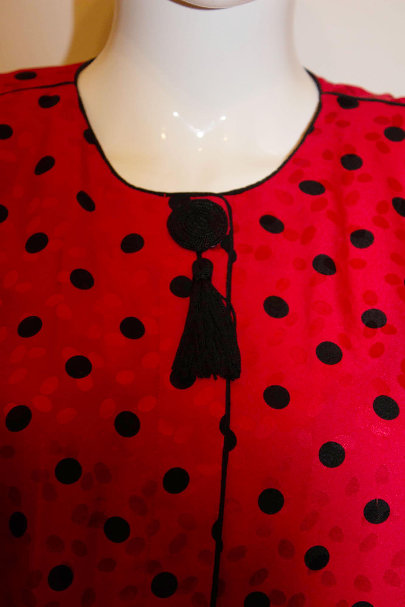 A fun vintage top by Maggy London . In a wonderful red silk with red and black dot detail. The top has a hidden button front opening, with tassle decoration, a silk knot cuffs. It has the original 1980s shoulder pads, but these can be removed.