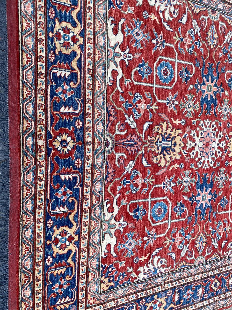 Discover the timeless elegance of our late 20th-century Mahal design Chobi Afghan rug. Hand-knotted with precision, this exquisite piece features a vibrant red backdrop adorned with decorative motifs, including repetitive patterns of stylized