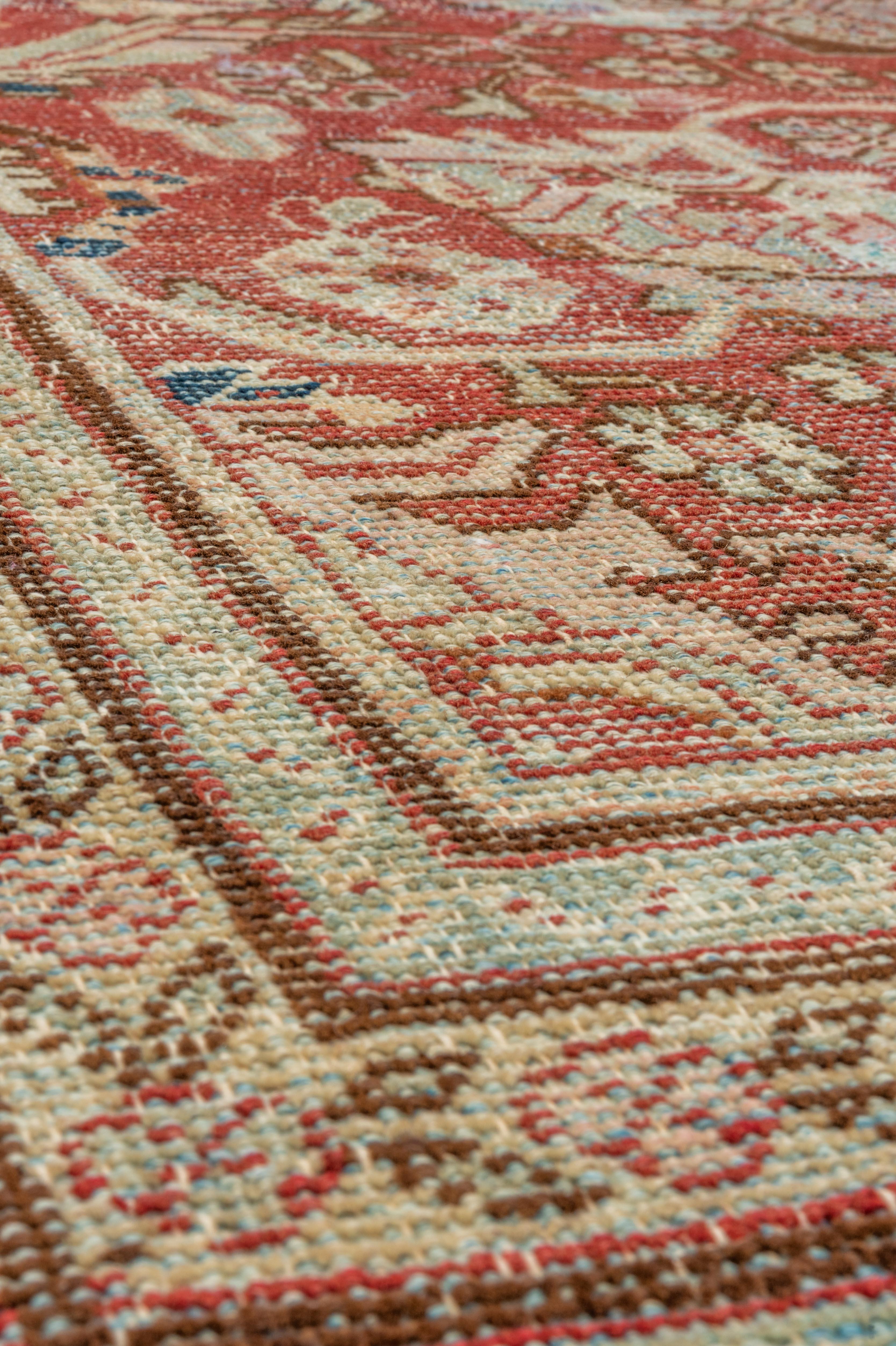 This vintage Mahal rug radiates soft, aged elegance with its central medallion flanked by stylized florals and palmettes, all rendered in weathered tones of brick red, dusty rose, pale aqua, and cream. The field features a harmonious allover