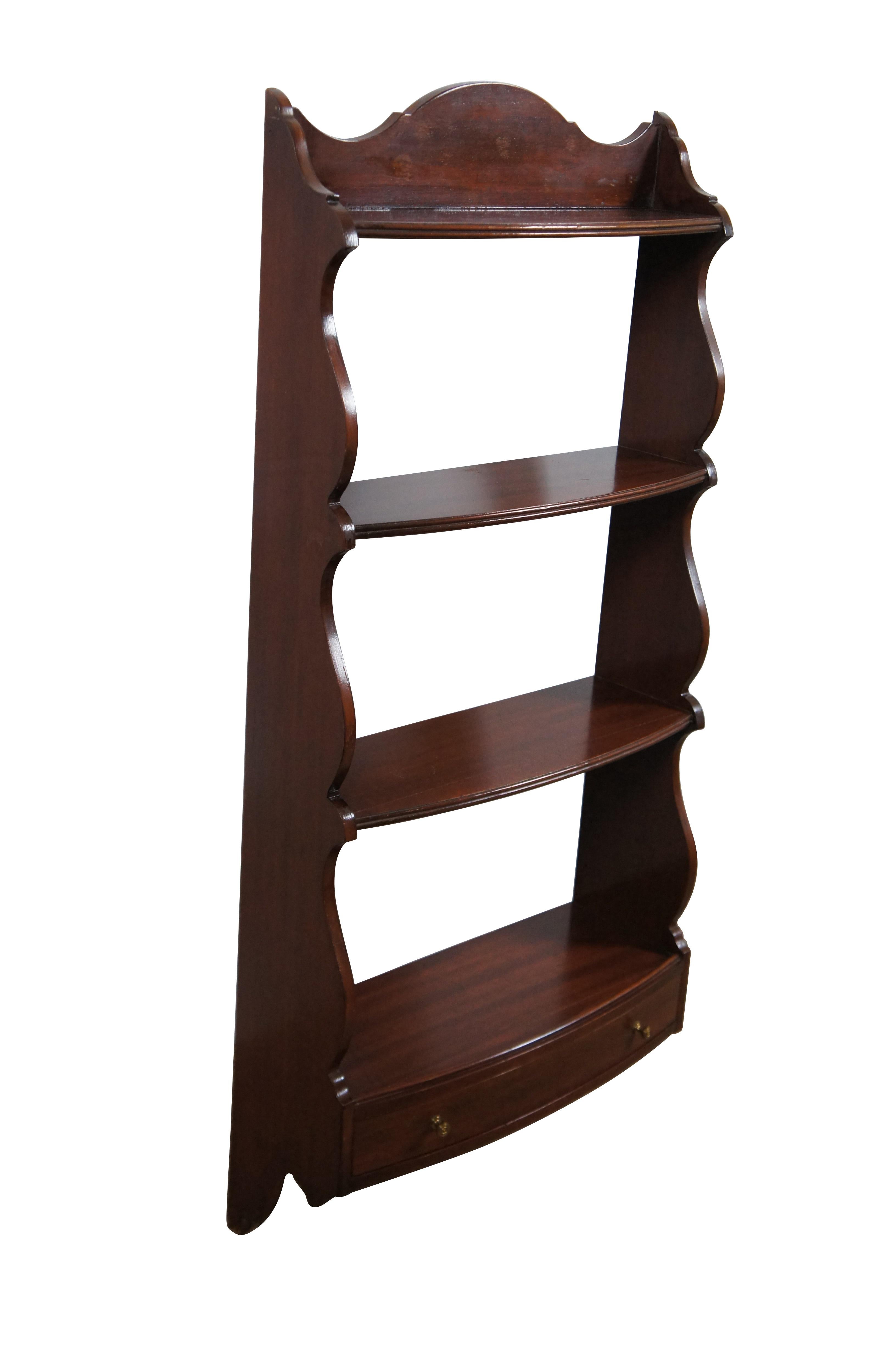 Large vintage mahogany wall hanging display shelf / curio featuring four shelves framed with serpentine sides, oxbow backsplash on top, and a bow front drawer with brass handles.

Dimensions:
16