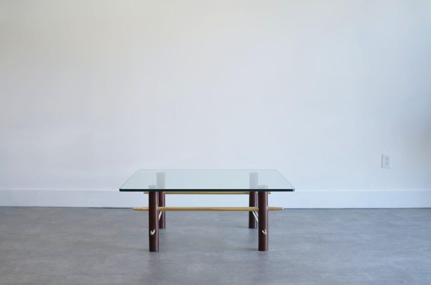 Exemple raffiné du design du milieu du siècle, cette table basse vintage est dans le style de AT&T. Robsjohn-Gibbings pour Widdicomb, vers 1952. Fabriqué avec quatre élégants piliers en acajou reliés par des brancards en laiton imbriqués, il