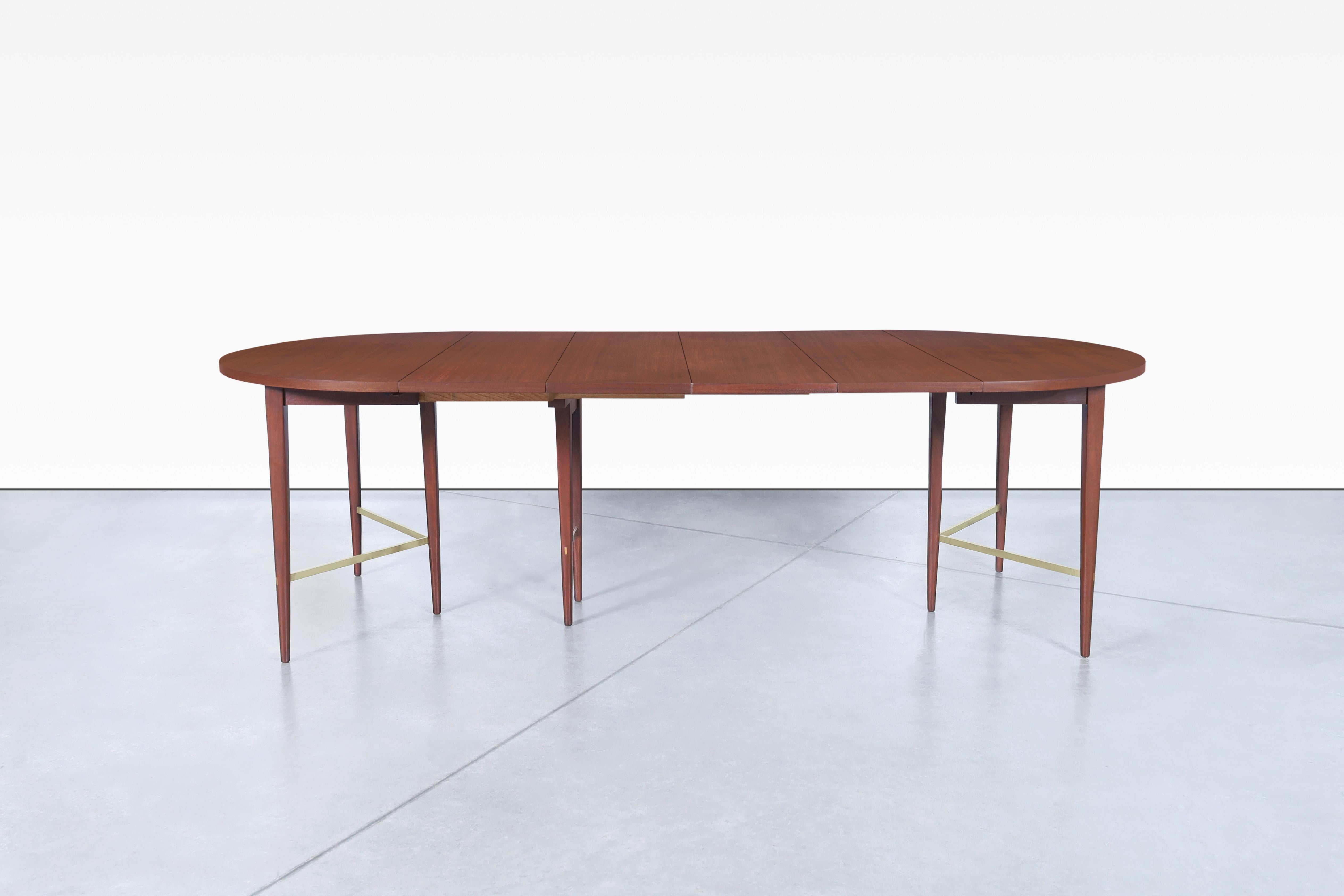 This stunning vintage dining table is a true masterpiece of mid-century design. Crafted from rich mahogany and solid brass, it was designed by the iconic Paul McCobb for Calvin Furniture as part of the Irwin Collection. The table features McCobb's