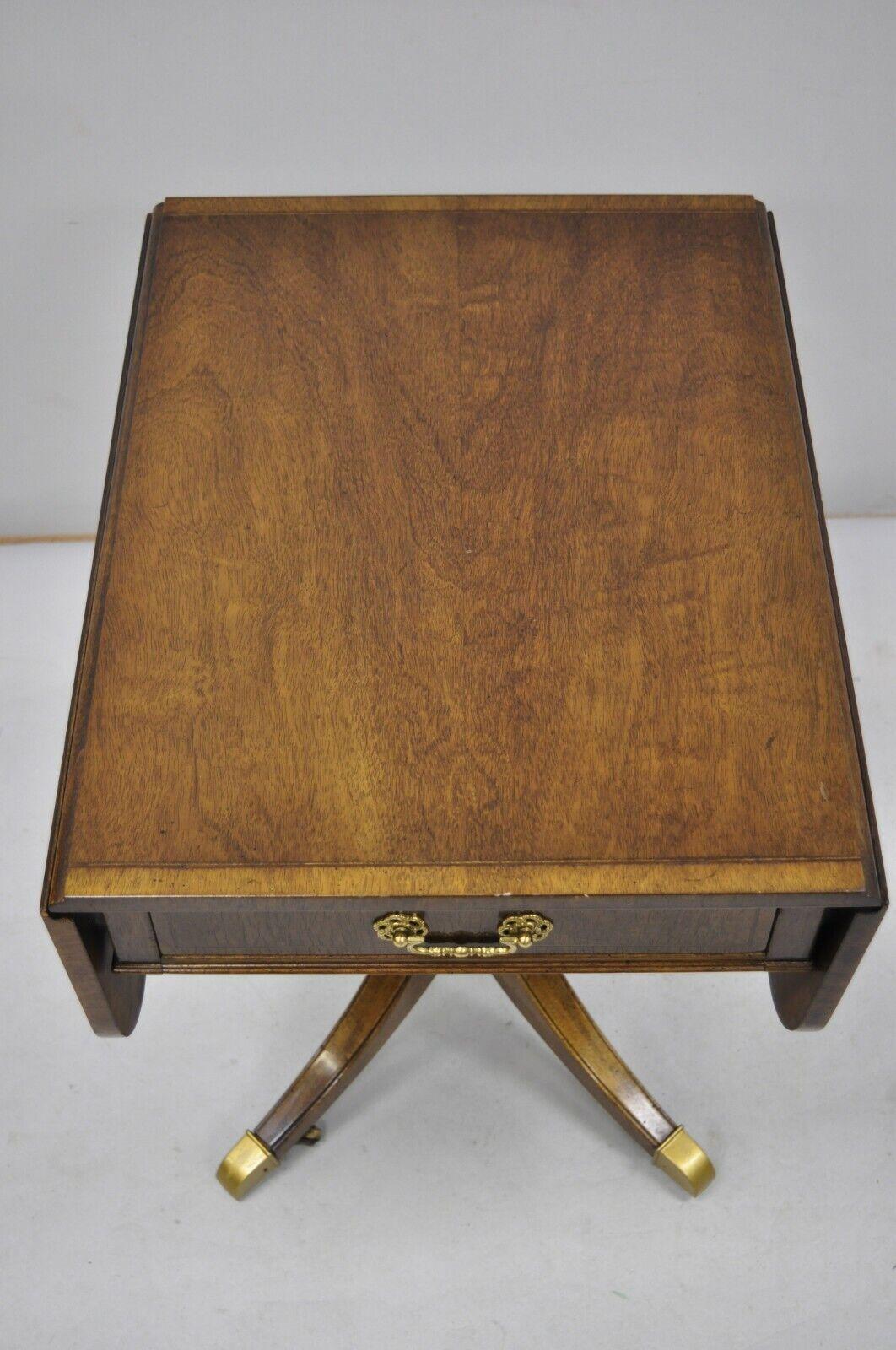 Vintage mahogany banded and inlaid drop leaf pembroke lamp side table. Item features banded and inlaid top, brass rolling casters, drop leaf sides, beautiful wood grain, 1 dovetailed drawer, solid brass hardware. Circa mid to late 20th century.