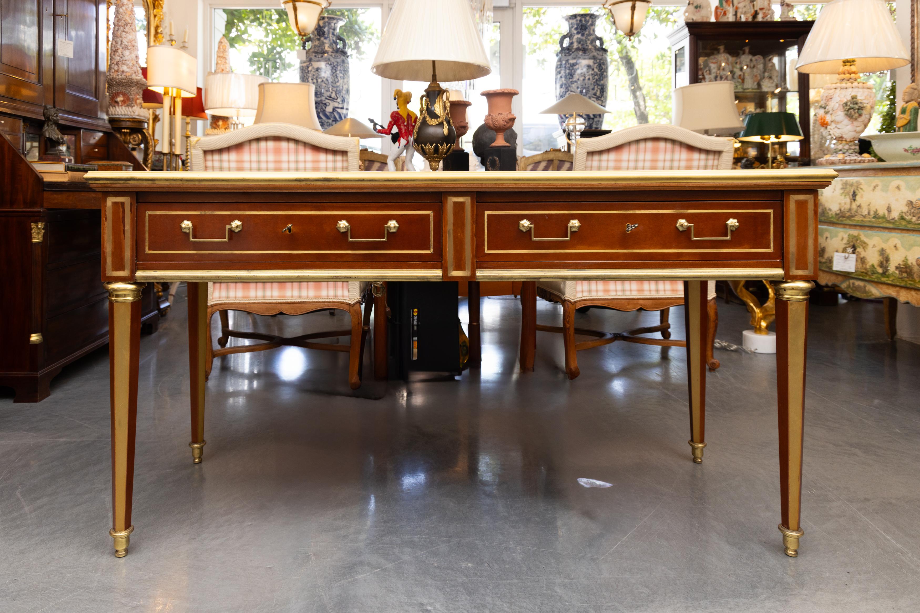 This is a versatile vintage mahogany sofa table/writing table with brass accents containing two frieze drawers and raised on round tapered legs.
