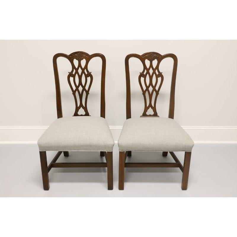 A pair of Chippendale style dining side chairs, unbranded, similar in quality to high-end furniture makers, such as Thomasville. Solid mahogany frame, fabric upholstery, carved backsplats; on a stretcher base with straight legs. Made in the USA in
