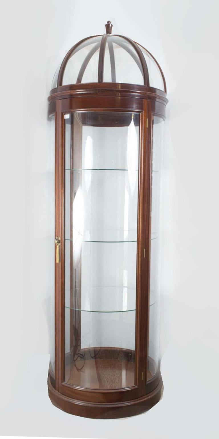 This is an exquisite and uniquely designed domed circular glass display cabinet, dating from the mid-20th century.

This tall circular display cabinet has been accomplished in solid mahogany and curved glass. Each side of the cabinet consists of a