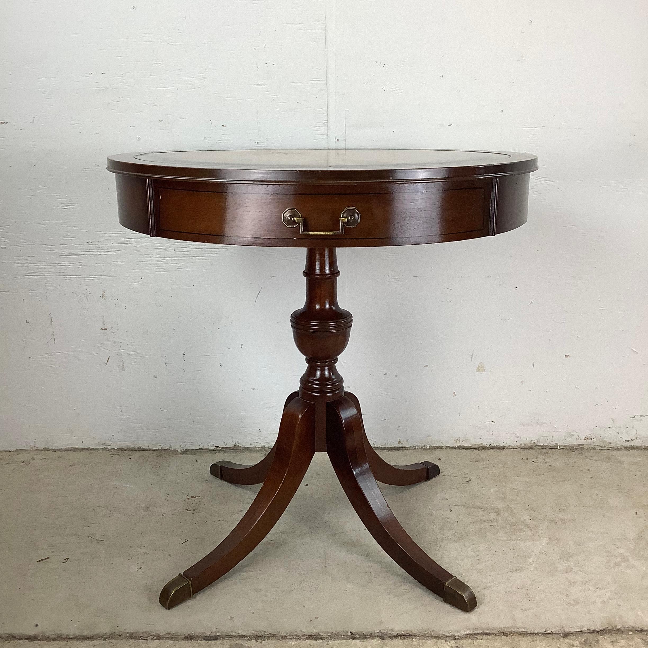 This vintage mahogany Duncan Phyfe style drum table with leather top is a stunning addition to any home or office, combining both style and practicality. The rich, deep tones of the mahogany wood create an inviting warmth, while the luxurious