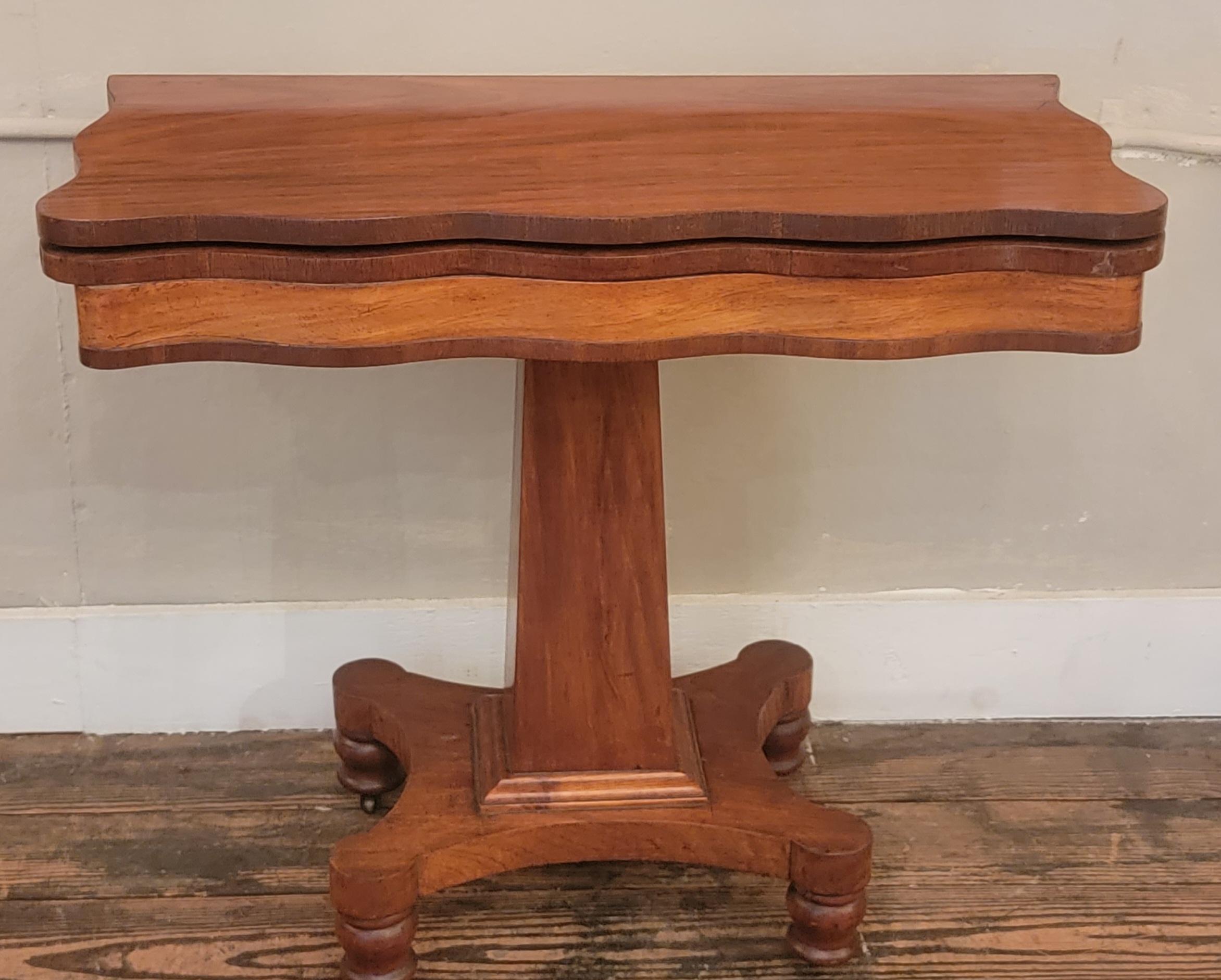 Versatile and handsome mahogany console table that opens to become a mediium sized game table.  The scalloped edges add a beautiful shape to the top and the pedestal base is classic.  When folded as a console, 16.5 d.