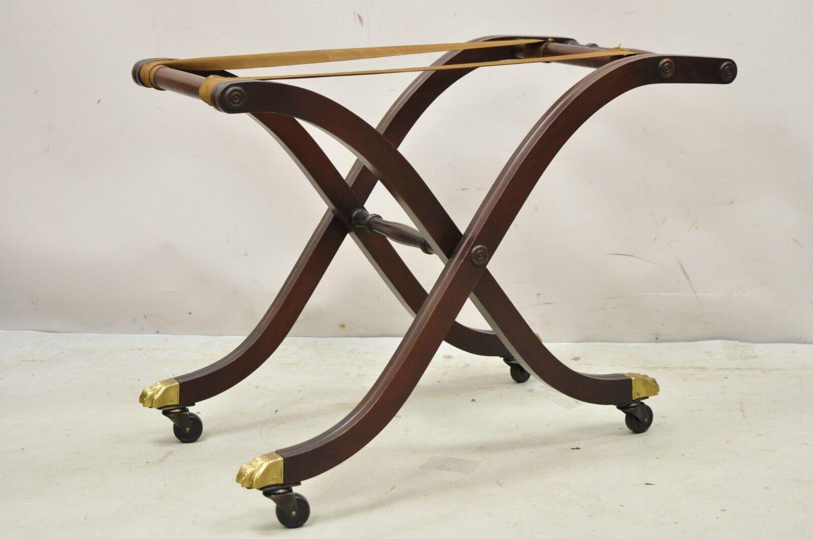 Vintage mahogany folding luggage rack stand rolling brass claw feet Empire Style. Item features a brass capped claw feet with rolling casters, fabric straps, folding frame, handle to side, solid mahogany wood frame, very nice vintage item. circa