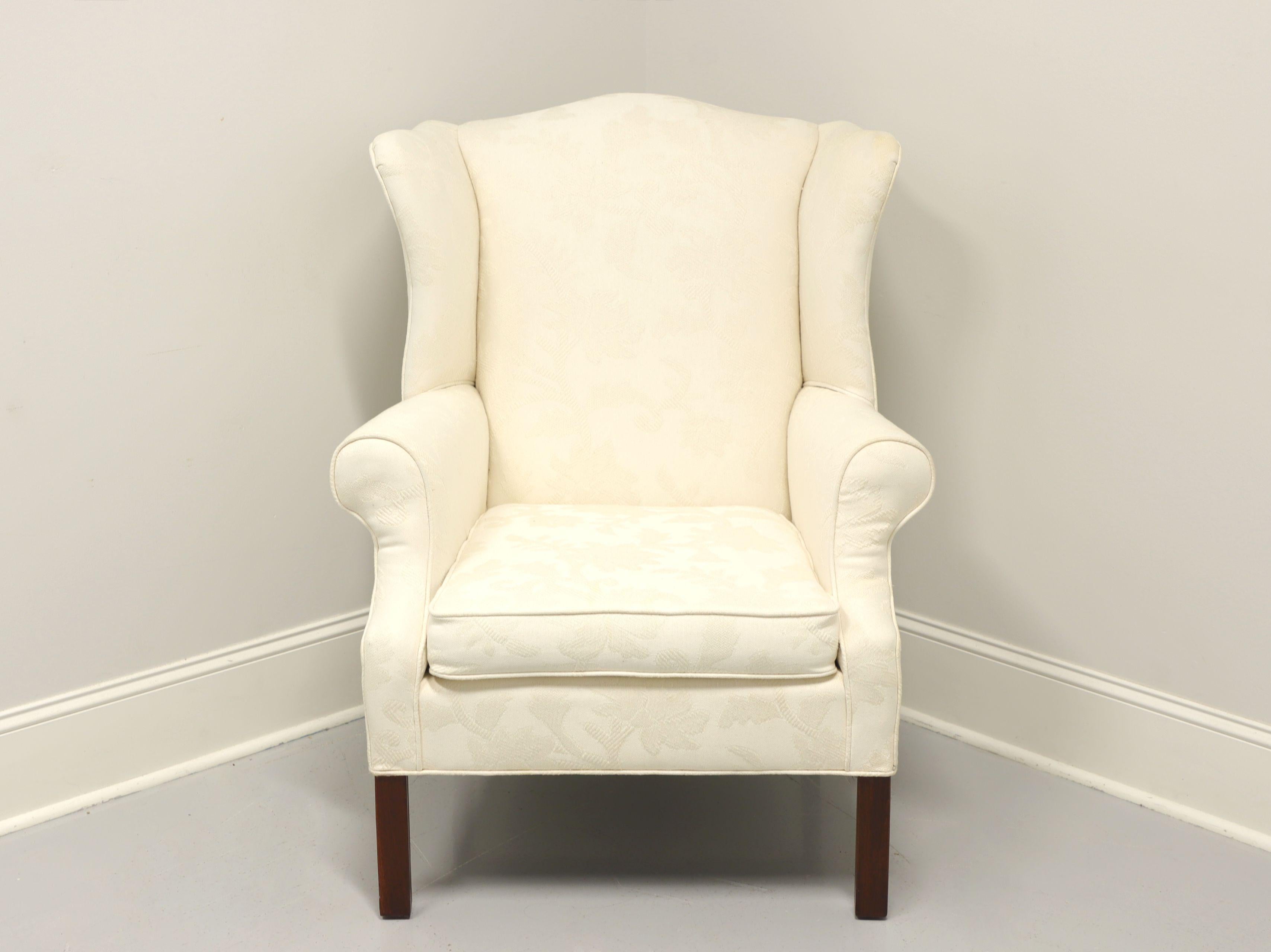 A Chippendale style wing back chair, unbranded, similar quality to Drexel or Hickory chair. Neutral cream colored raised pattern fabric upholstery on a mahogany frame with straight legs. Made in the USA, in the late 20th Century.

Measures: overall: