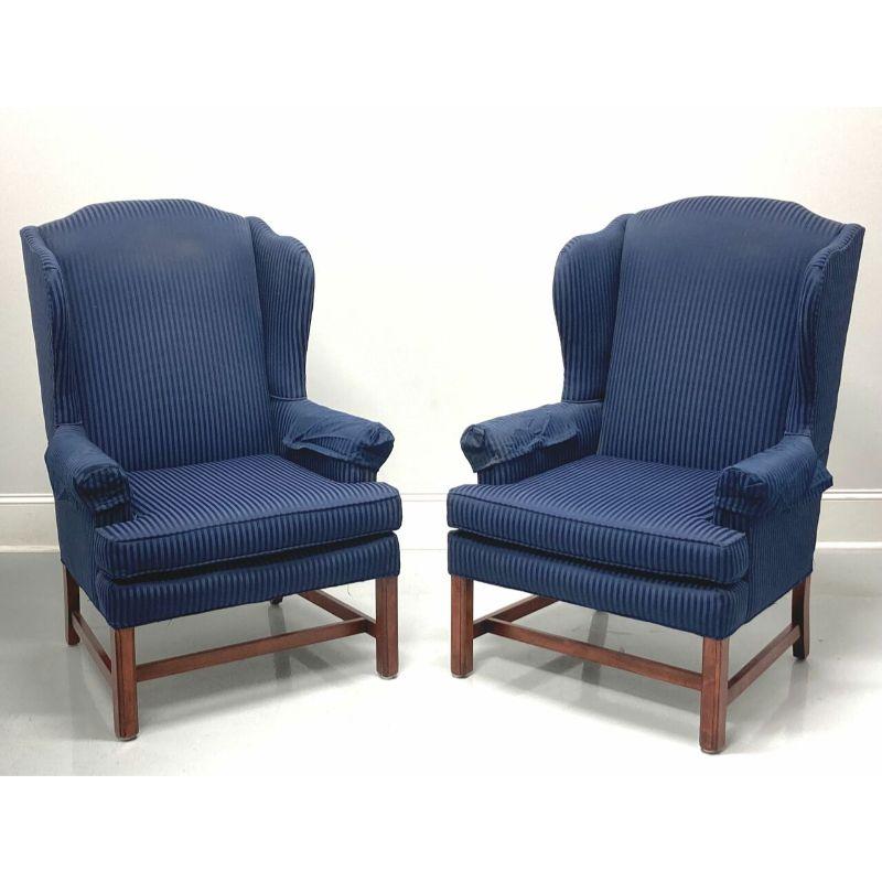 A pair of Chippendale style wing back chairs, unbranded, similar quality to Drexel or Hickory chair. Navy blue damask stripe pattern fabric upholstery on a mahogany frame with straight legs and stretcher base. Made in the USA, in the late 20th