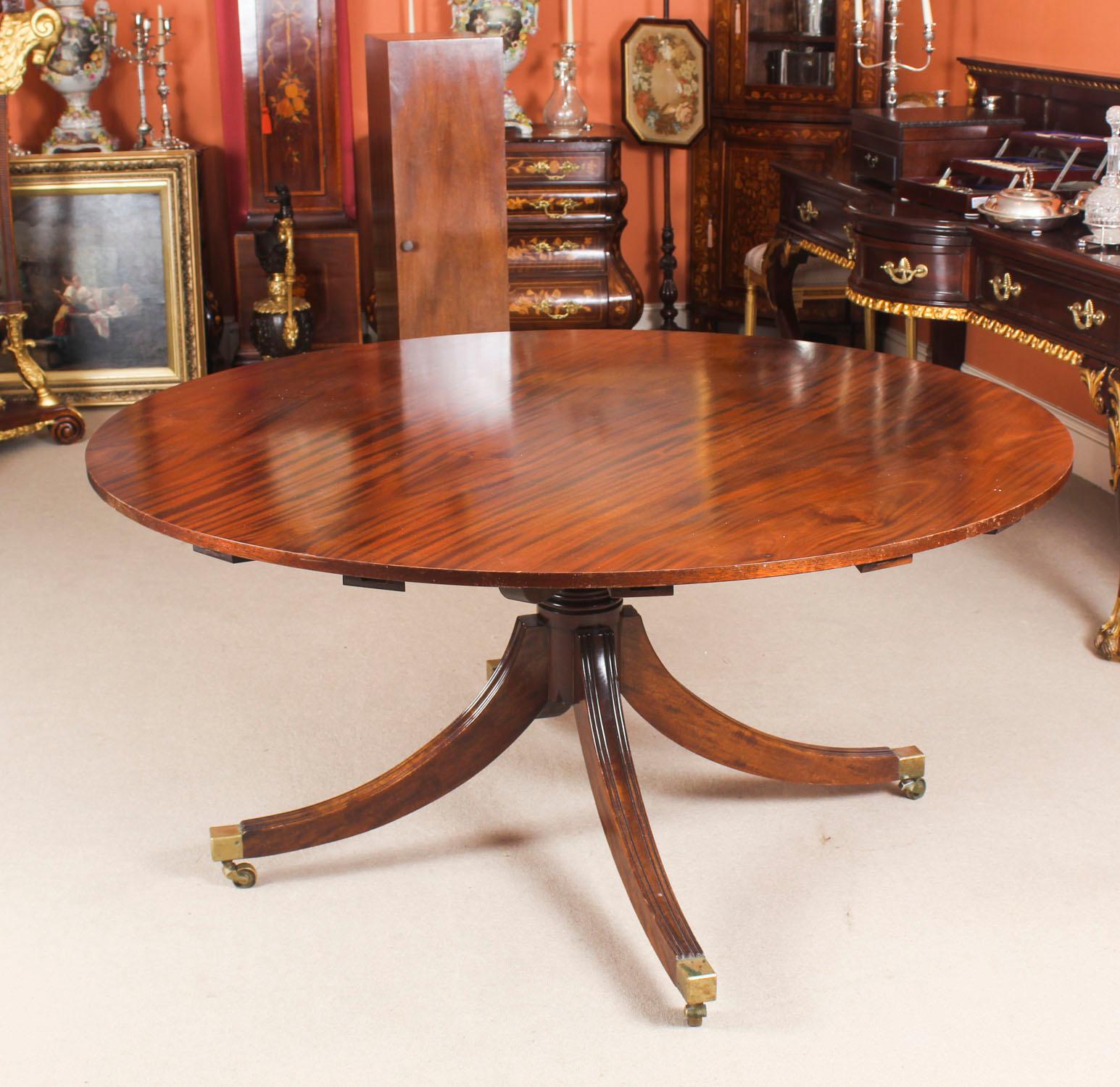 This is a beautiful Regency Revival Jupe style flame mahogany dining table, dating from the mid 20th Century.

The table has a solid mahogany top with a reeded edge that has five additional outer extension leaves that can be added around the